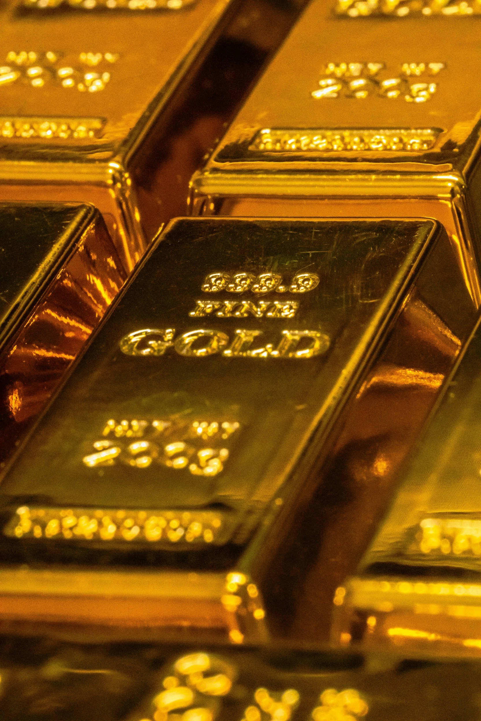 Close-up of gold bars stacked together, each inscribed with weight and purity.