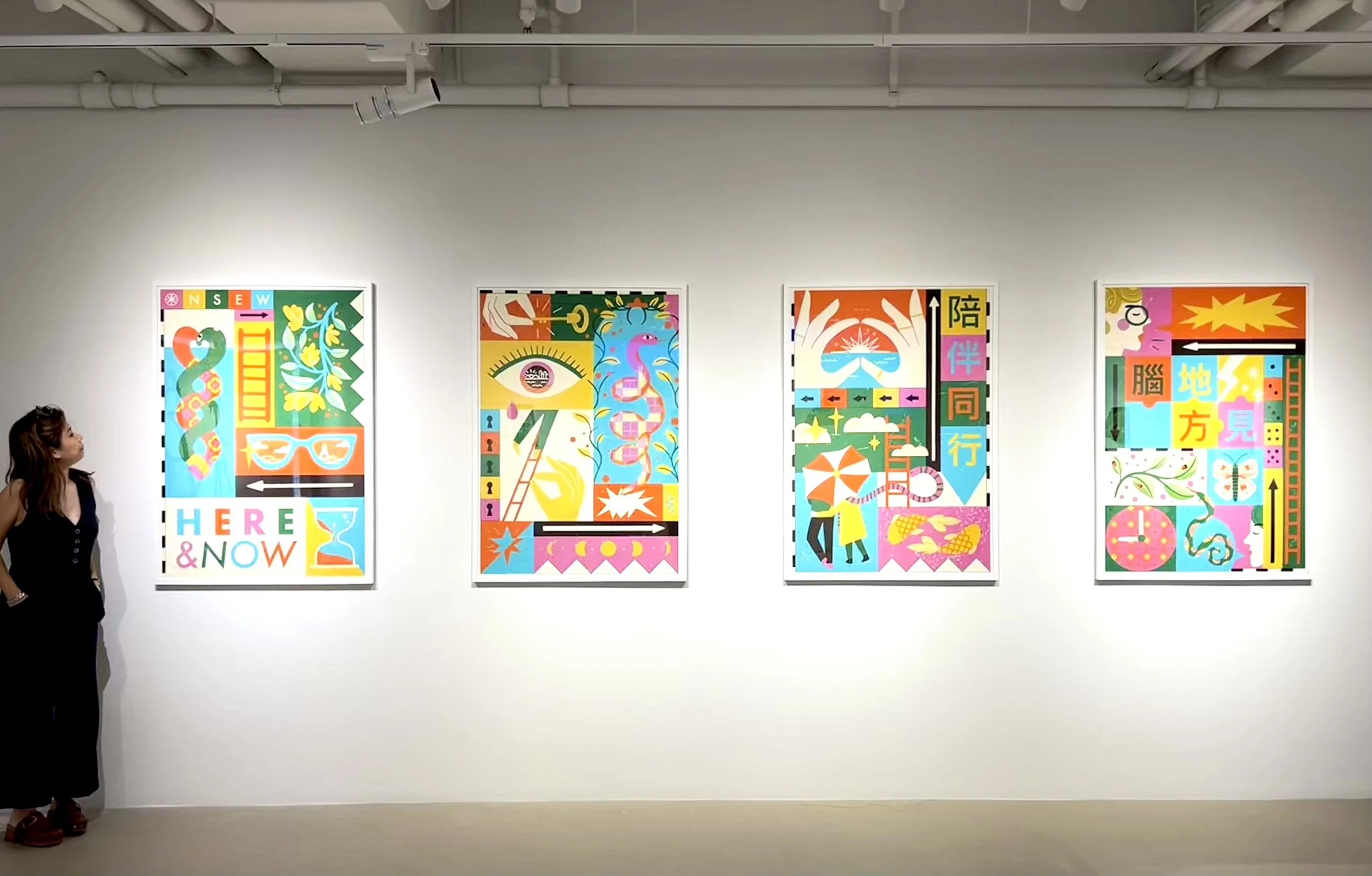 Four colorful modern art paintings hanging on a gallery wall with a woman observing them, and a woman with sunglasses on her head dressed in black on the left side of the image.