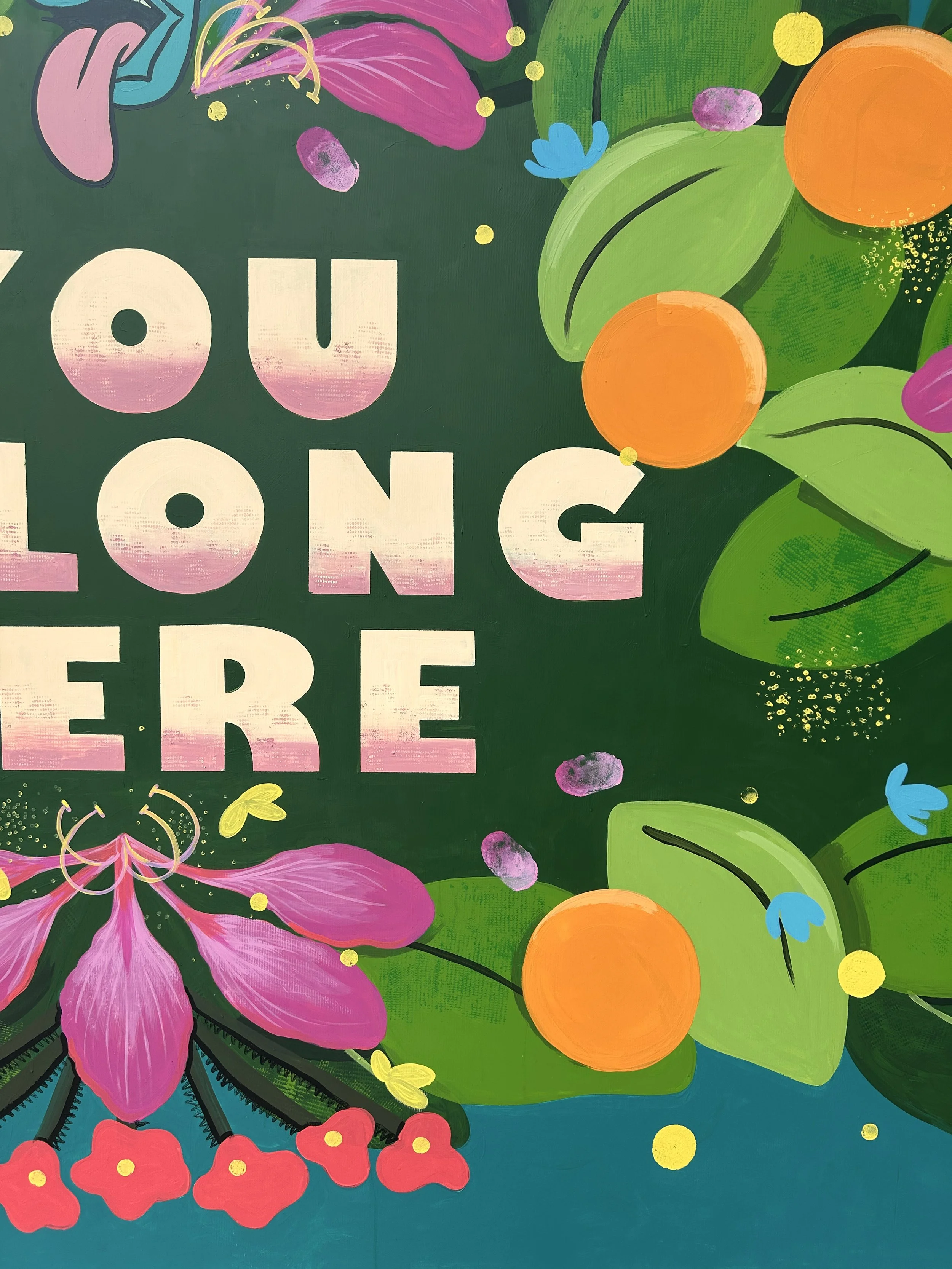 Colorful mural with the phrase 'You Long Here' surrounded by vibrant floral and foliage designs including pink flowers, orange circles, green leaves, and small yellow and purple accents.