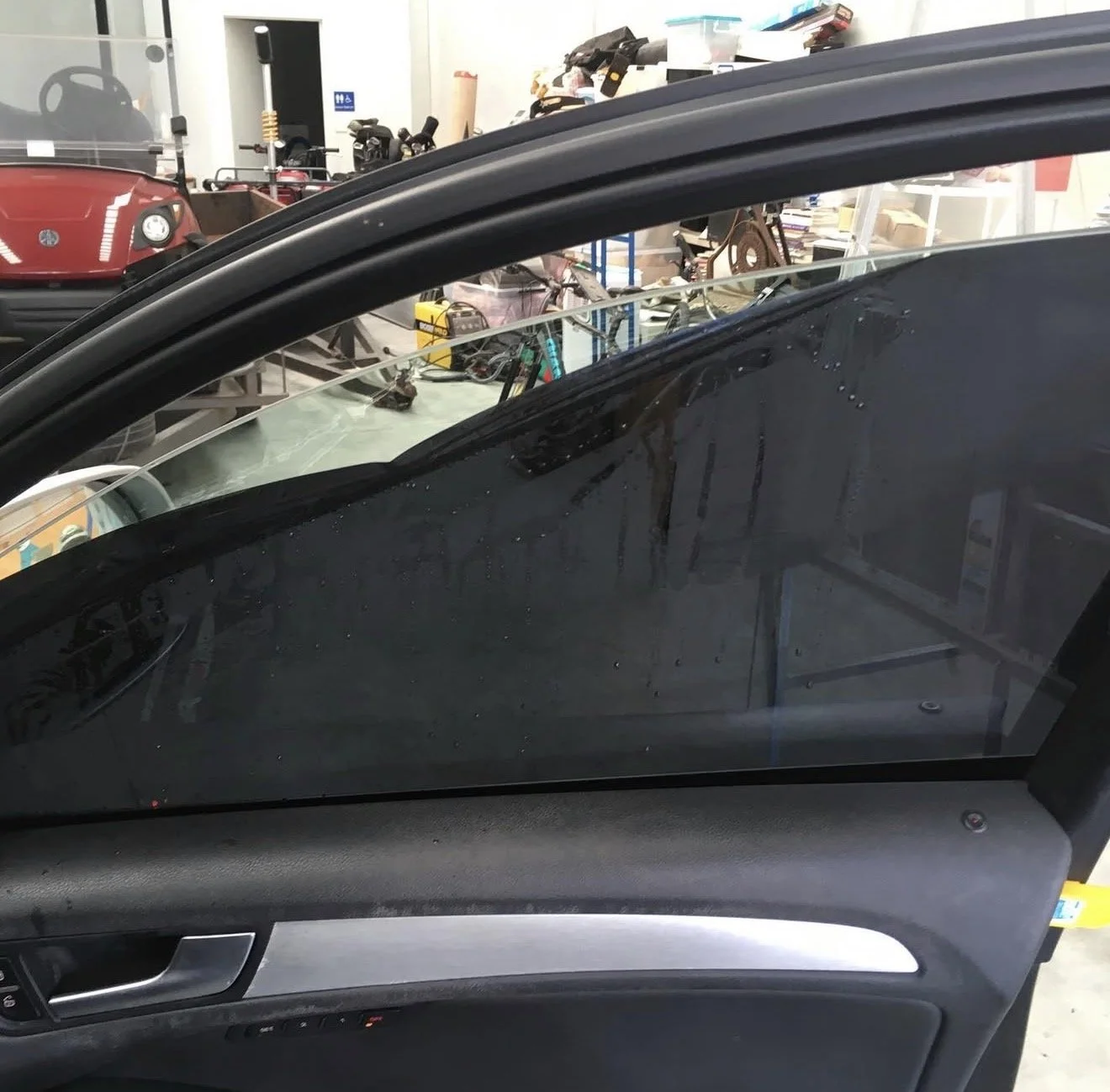 The image shows the inside of a car with its front driverwindow getting the tint removed.