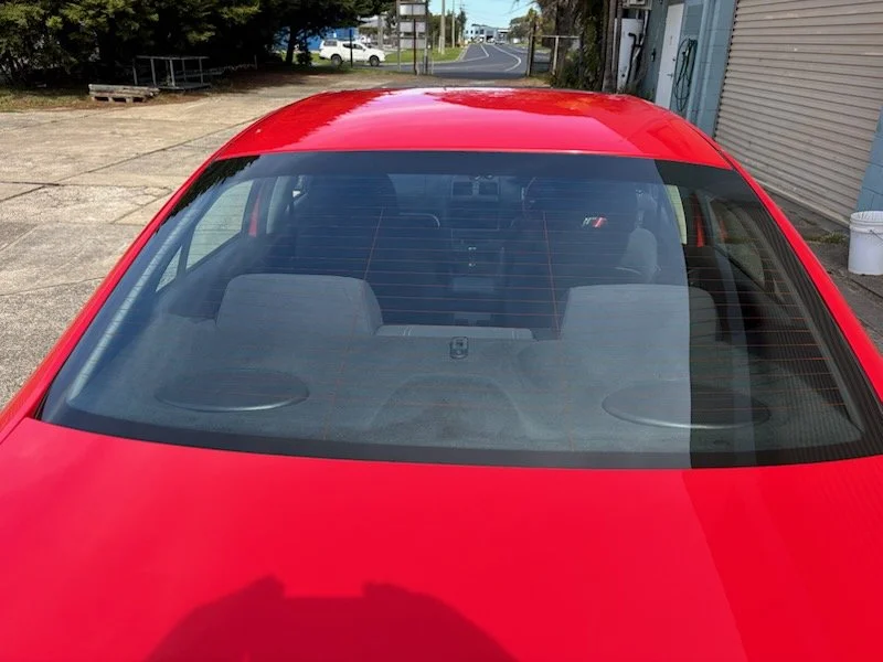 Red car viewed from the rear windshield, showing the back seats and interior. without tint