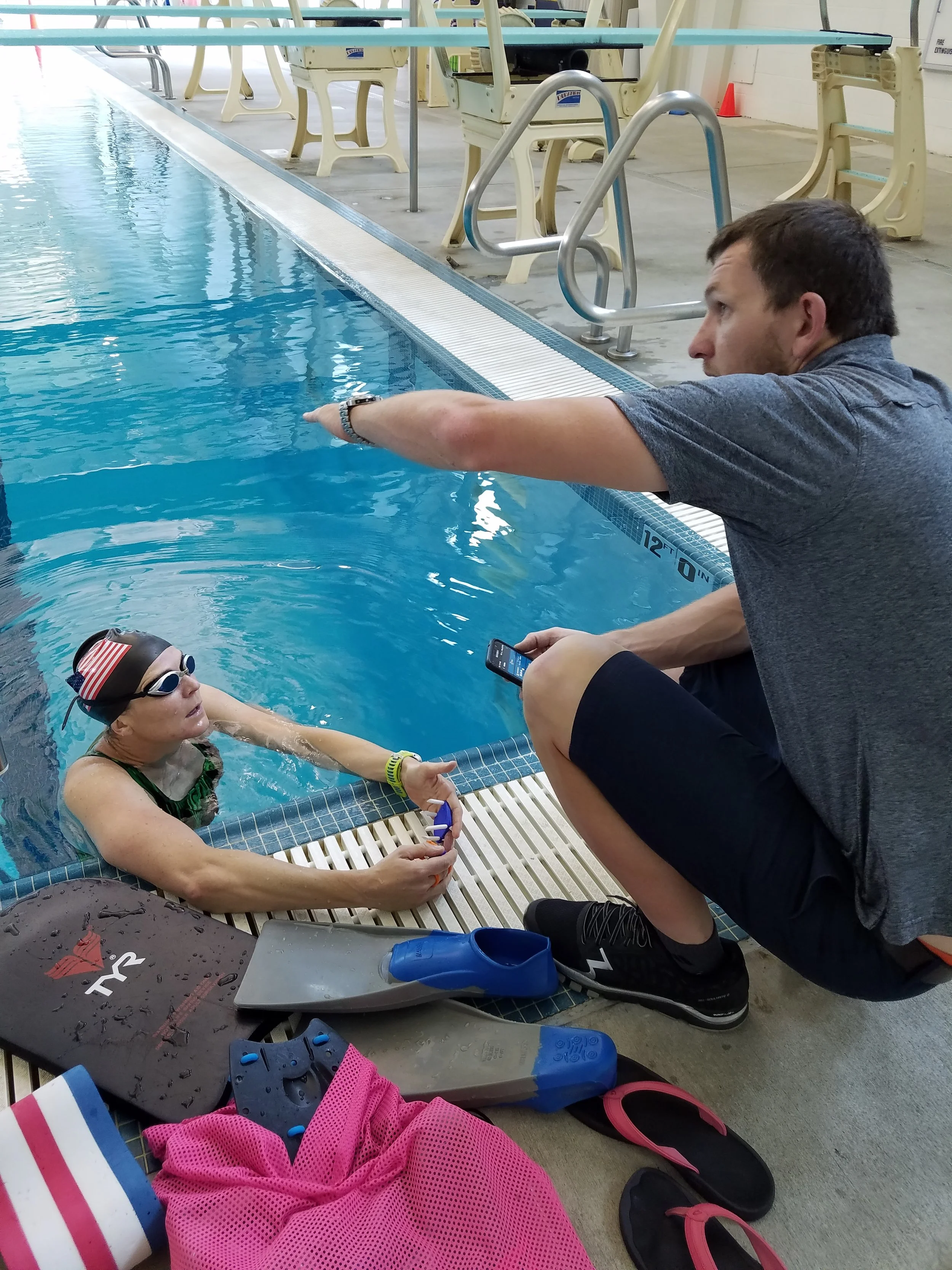 Simon providing coaching to an athlete in a swimming pool.