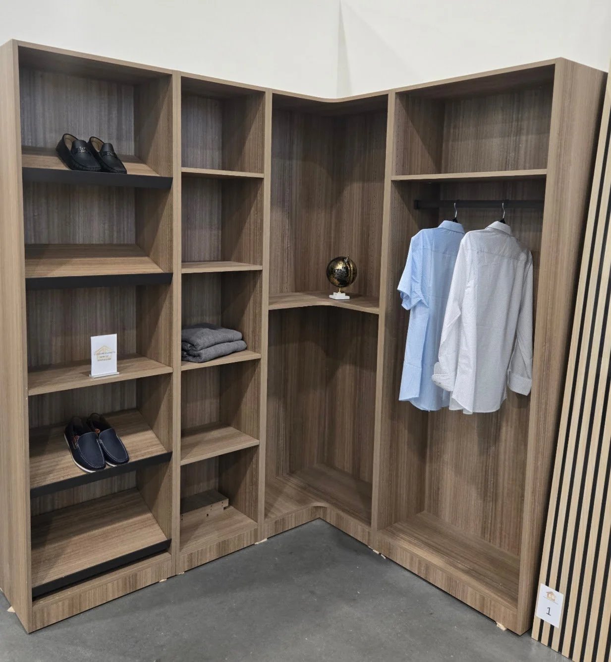 Empty wooden closet with shelves, hanging clothes, shoes, and a small globe decoration inside.