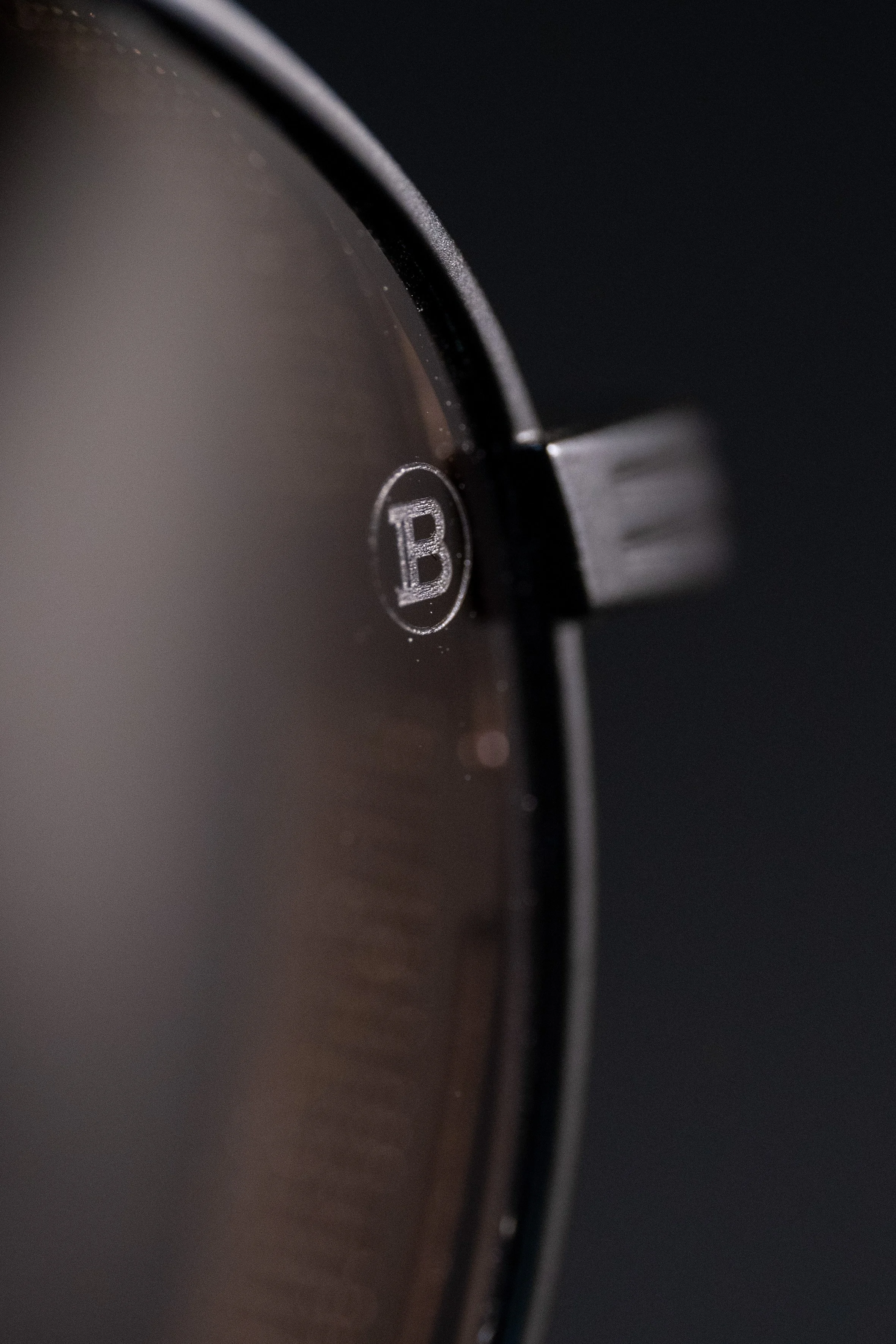 Close-up of a black circular device with a small dial and a central logo with the letter B.