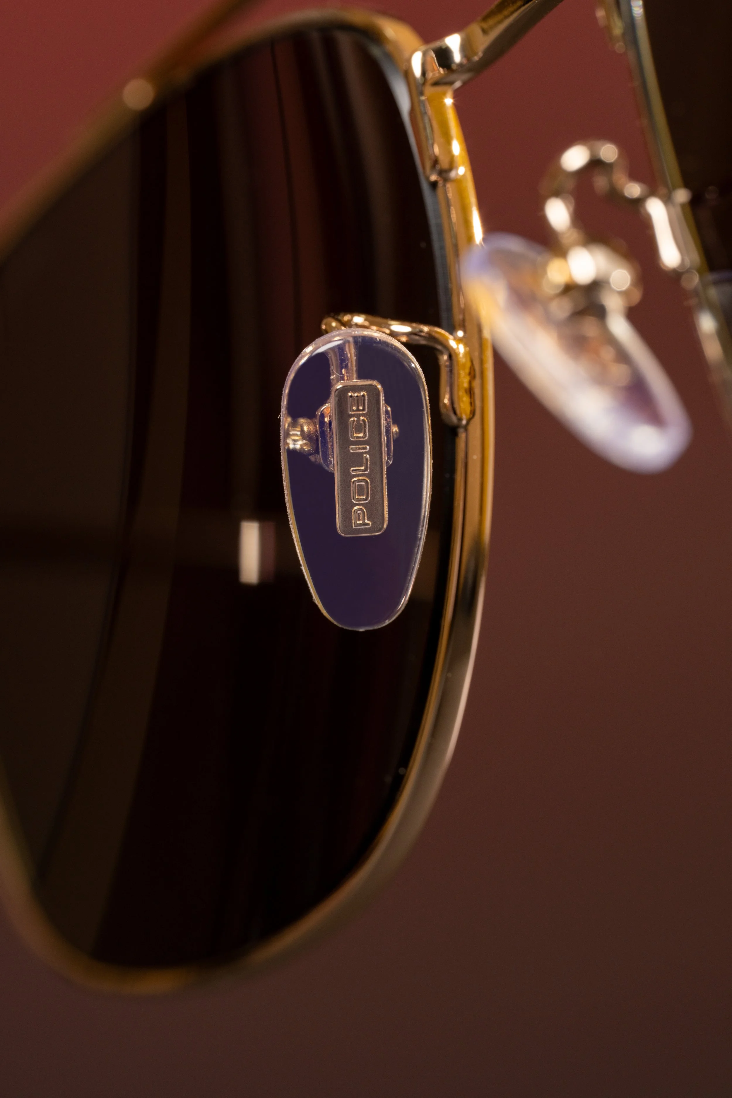 Close-up of a police badge attached to the side of a dark pair of sunglasses with gold framing.