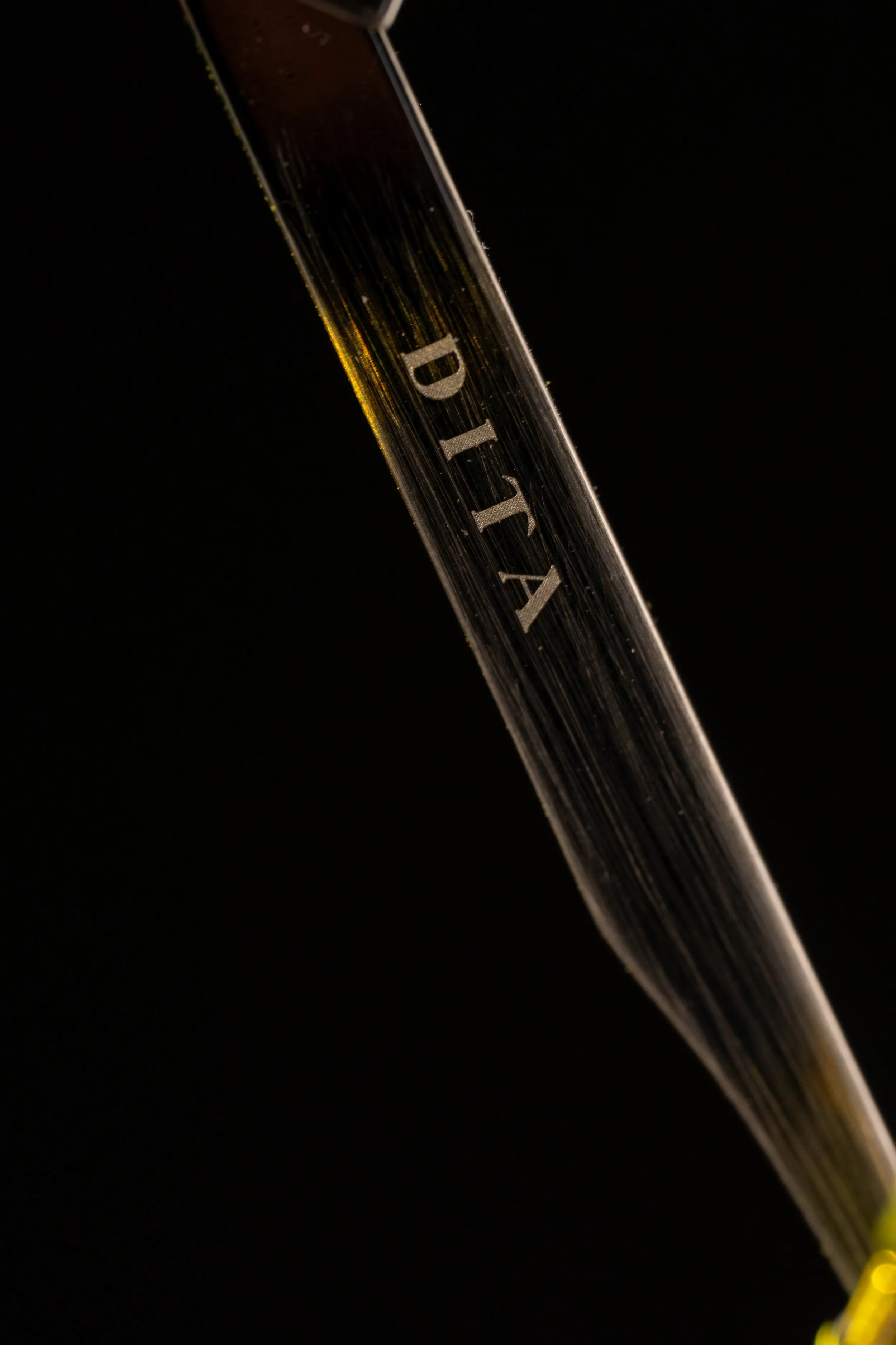 Close-up of a glass pipette with the brand name 'D AIK' etched on it, set against a black background.