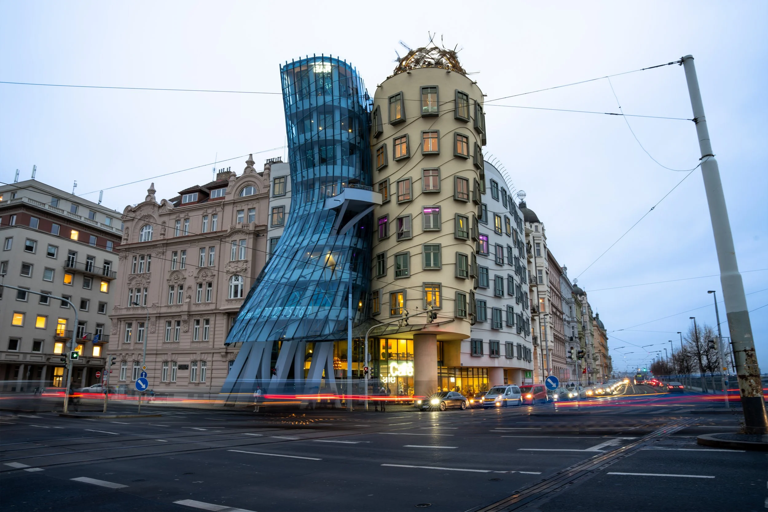 Exterior of the Casa Mila building, also known as La Pedrera, in Barcelona, Spain, with architectural design featuring curving shapes and a glass elevator shaft on the facade during dusk.