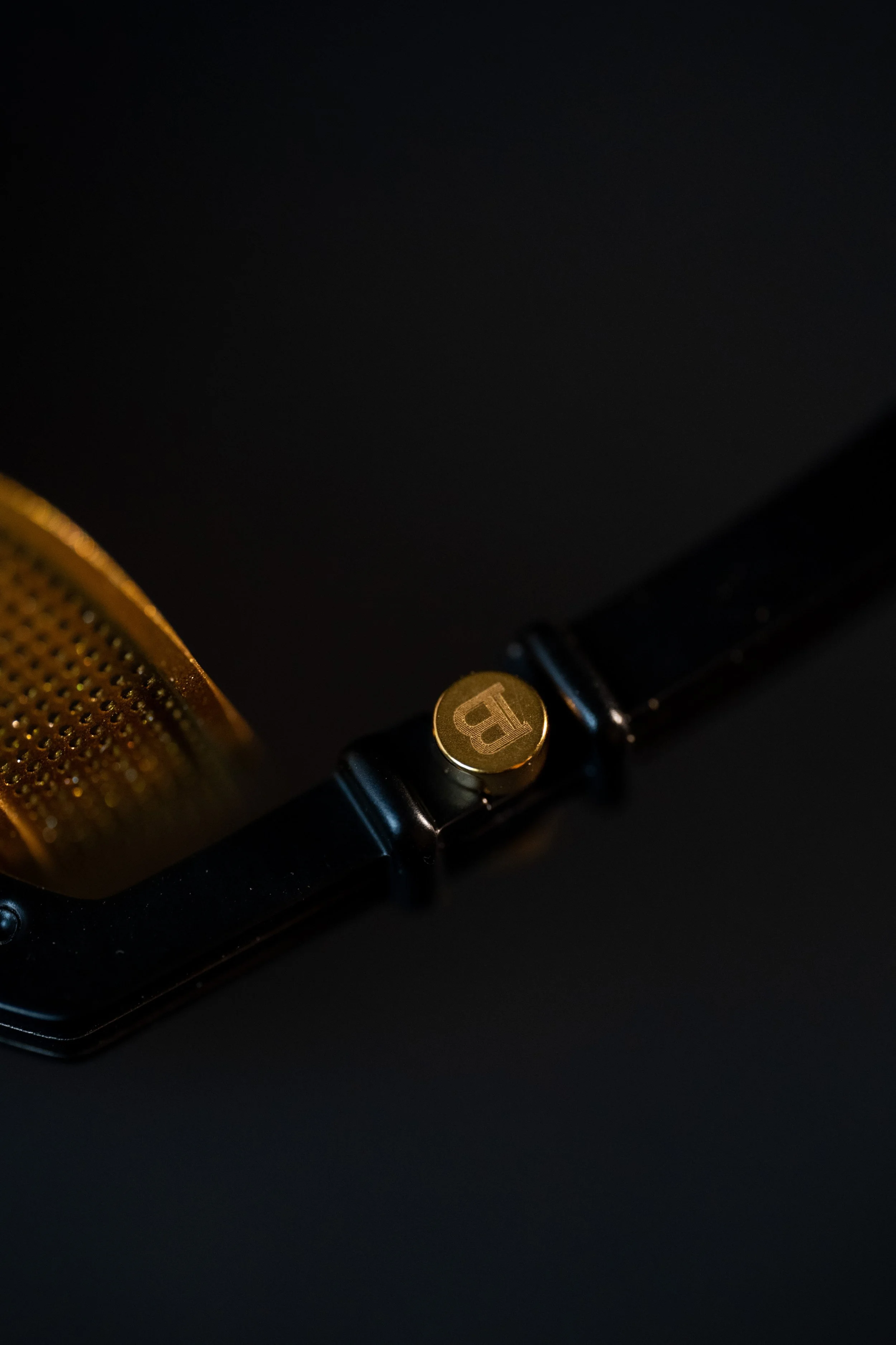 Close-up of a microphone with a gold-colored grille and a black body, featuring a gold emblem with a 'B' on a black background.
