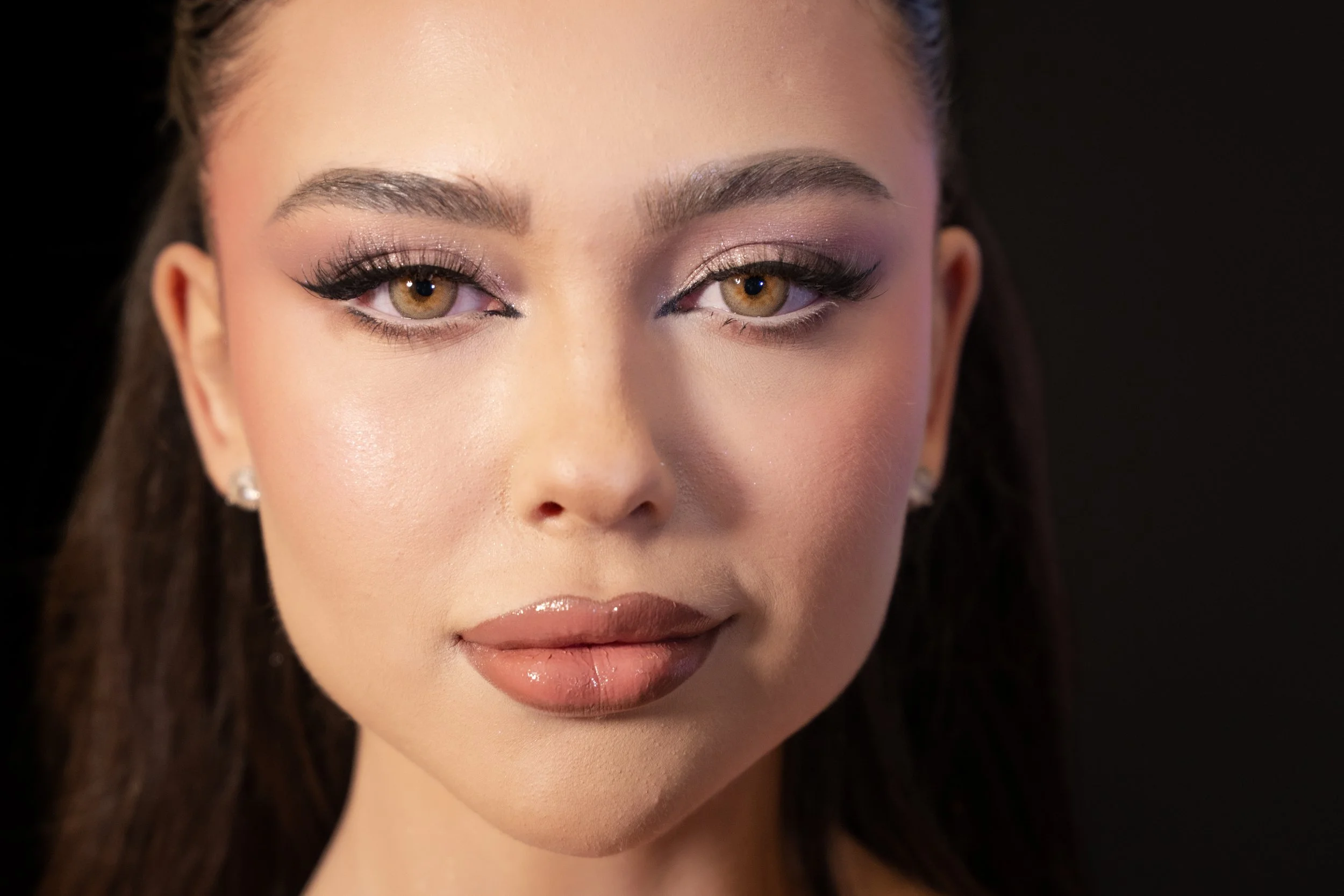 Close-up of a woman's face with makeup, including eyeshadow, eyeliner, mascara, and lipstick.