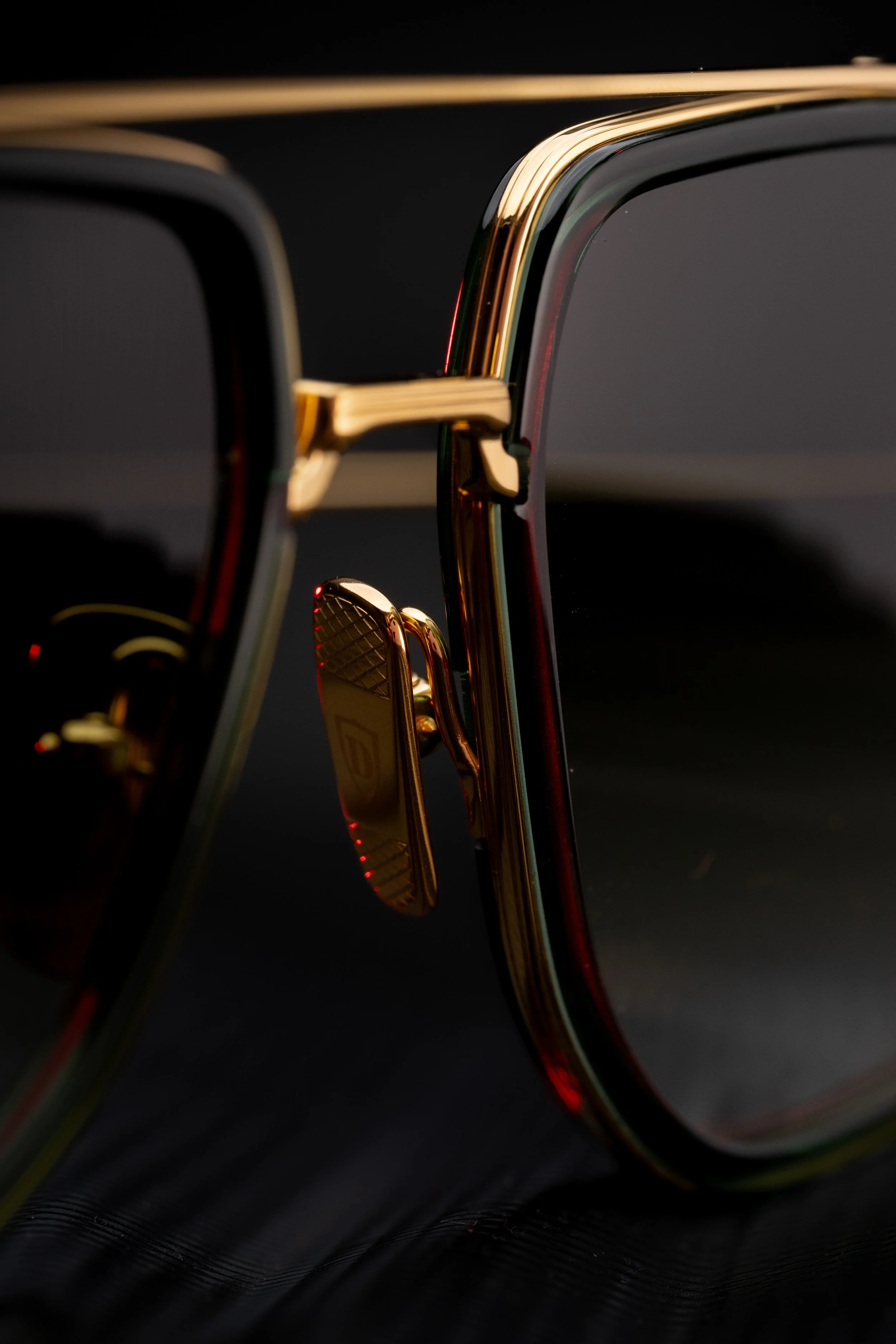 Close-up of a pair of sunglasses with gold accents and black lenses, on a dark surface.