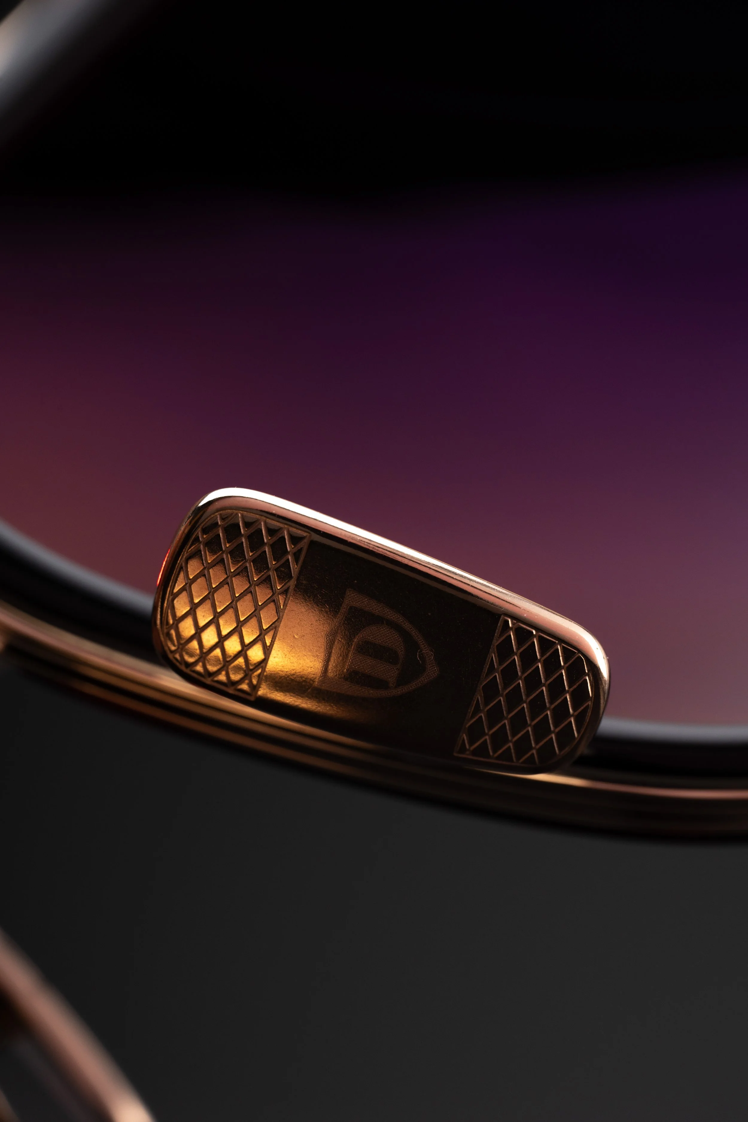 Close-up of a Rolex watch crown with a gold finish and embedded logo.