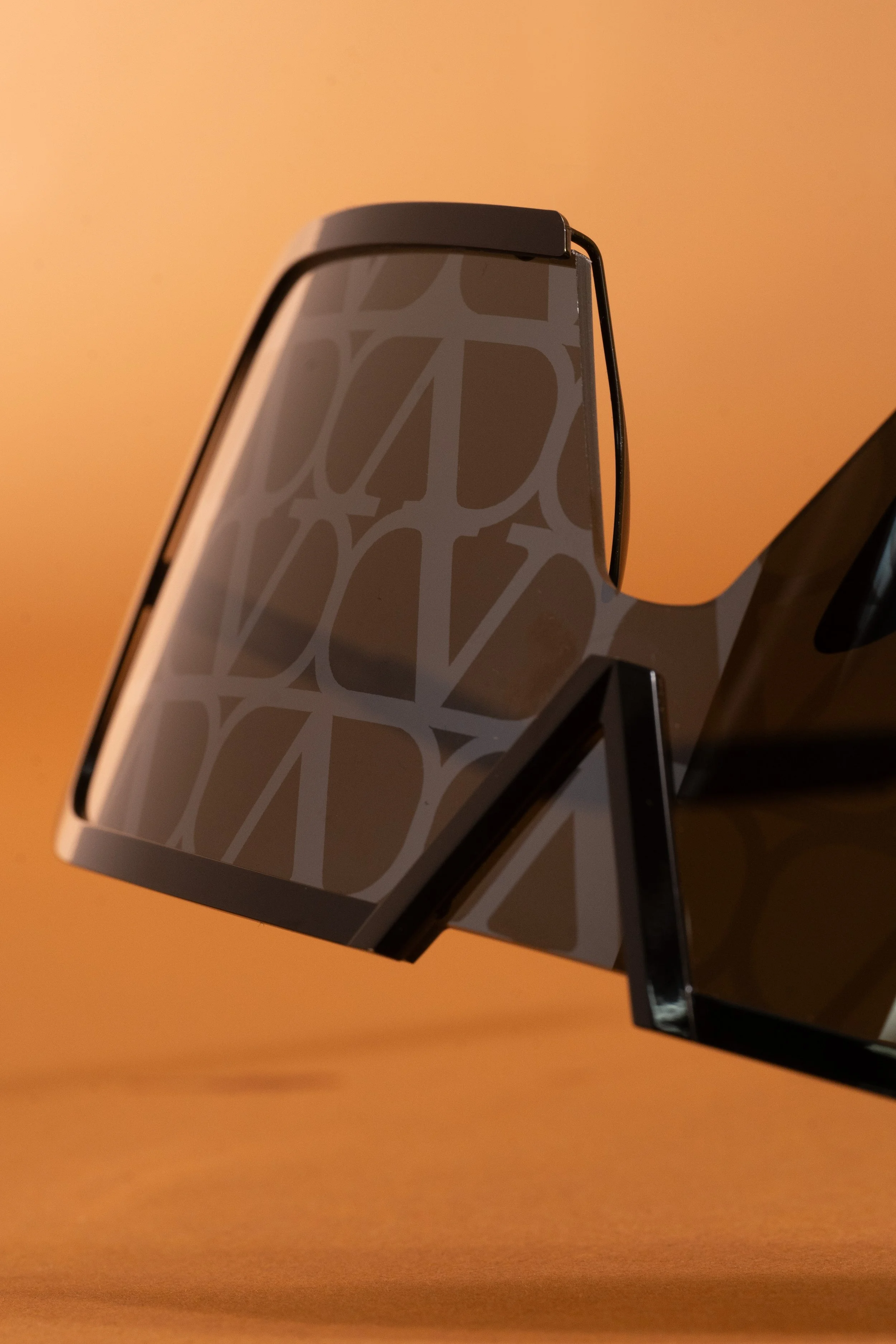 Close-up of a computer monitor with a patterned stand against a warm orange background.