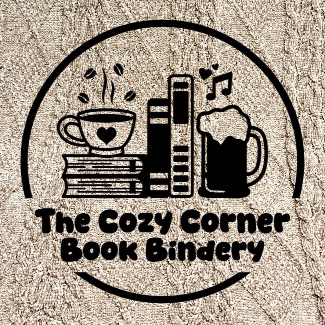 Logo for The Cozy Corner Book Bindery, featuring illustrations of a steaming coffee cup, books, a beer mug, and musical notes, all enclosed in a circle over a tan blanket background. Bookbinding classes, Sioux City, Iowa.