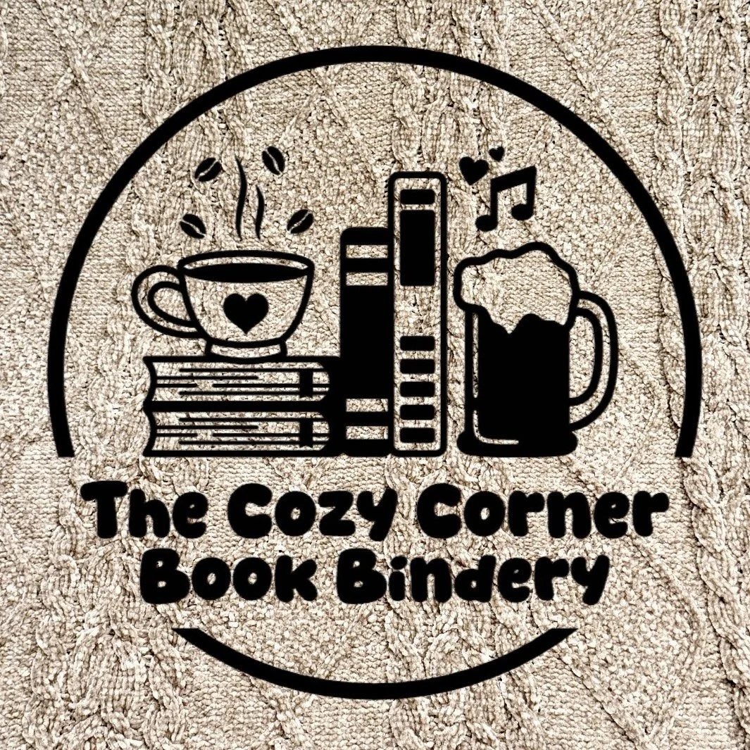 Logo for The Cozy Corner Book Bindery, featuring illustrations of a steaming coffee cup, books, a beer mug, and musical notes, all enclosed in a circle over a tan blanket background