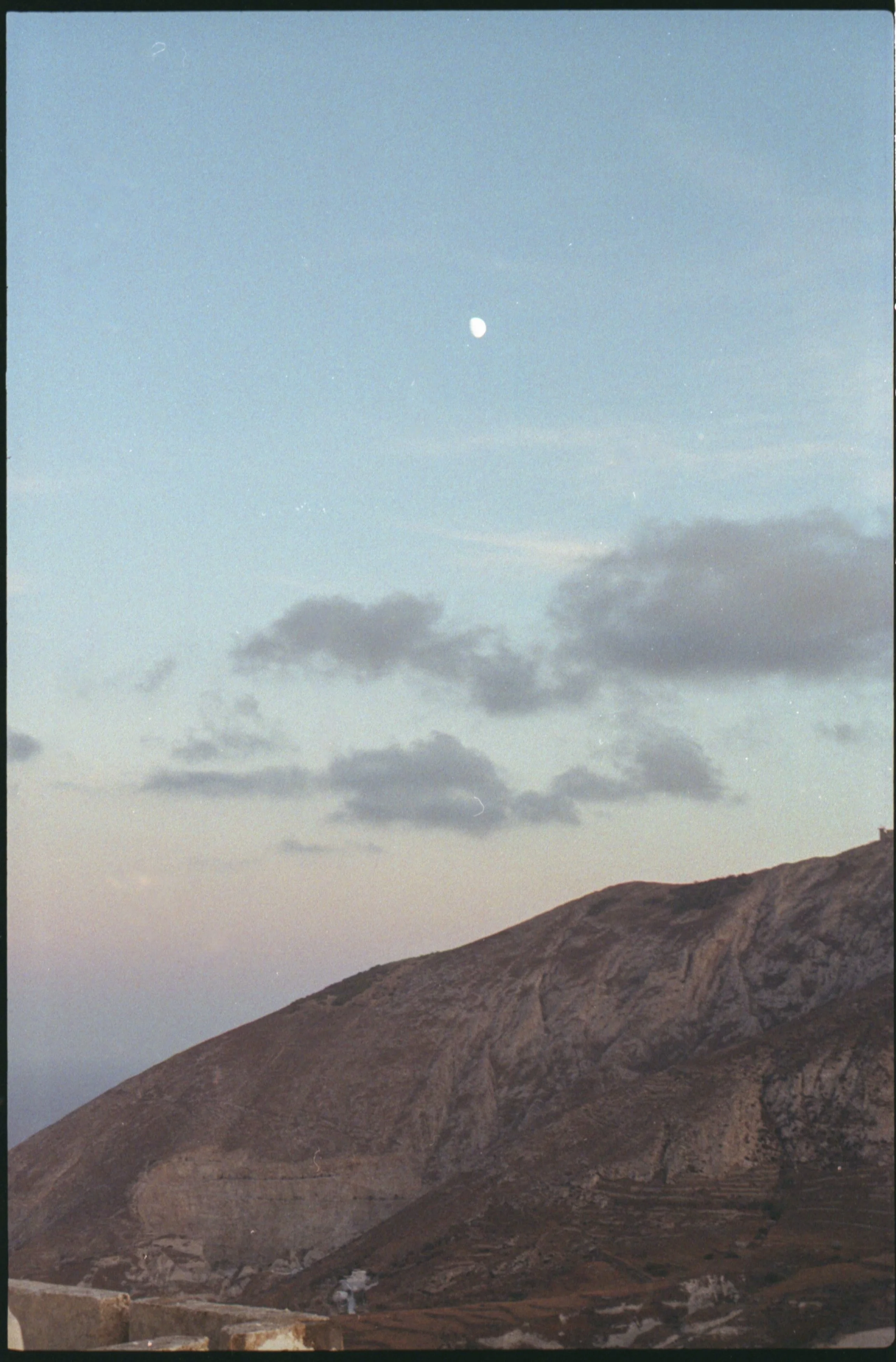 Un paysage de montagne avec le ciel bleu, quelques nuages et la lune