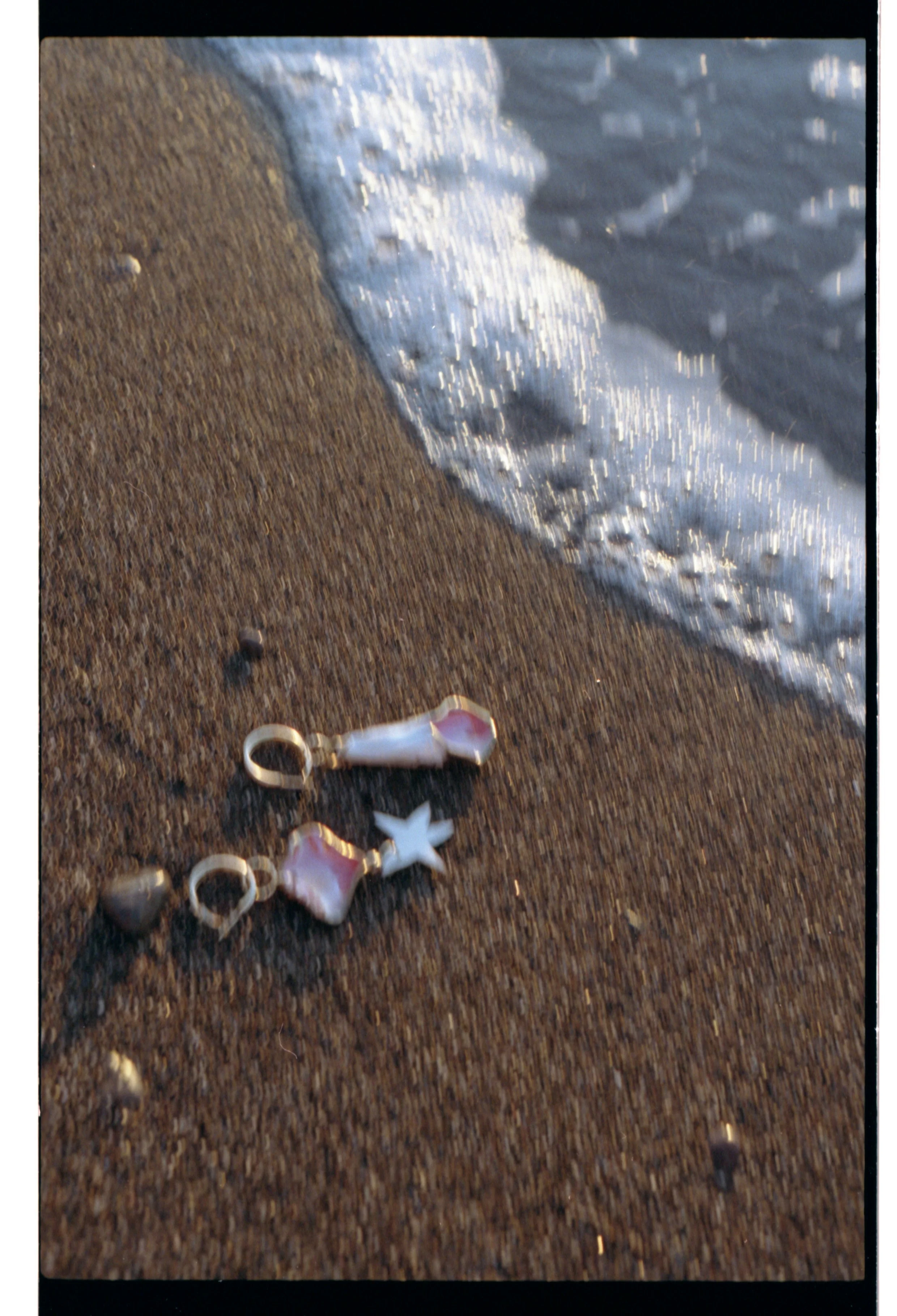Charms de coquillage sur le sable près de l'eau de mer, avec des vagues approchant la plage.