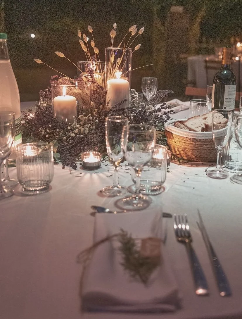 Table de dîner décorée avec des bougies, des verres à vin, une bouteille de vin, un panier de pain et une nappe blanche, ambiance chaleureuse et élégante