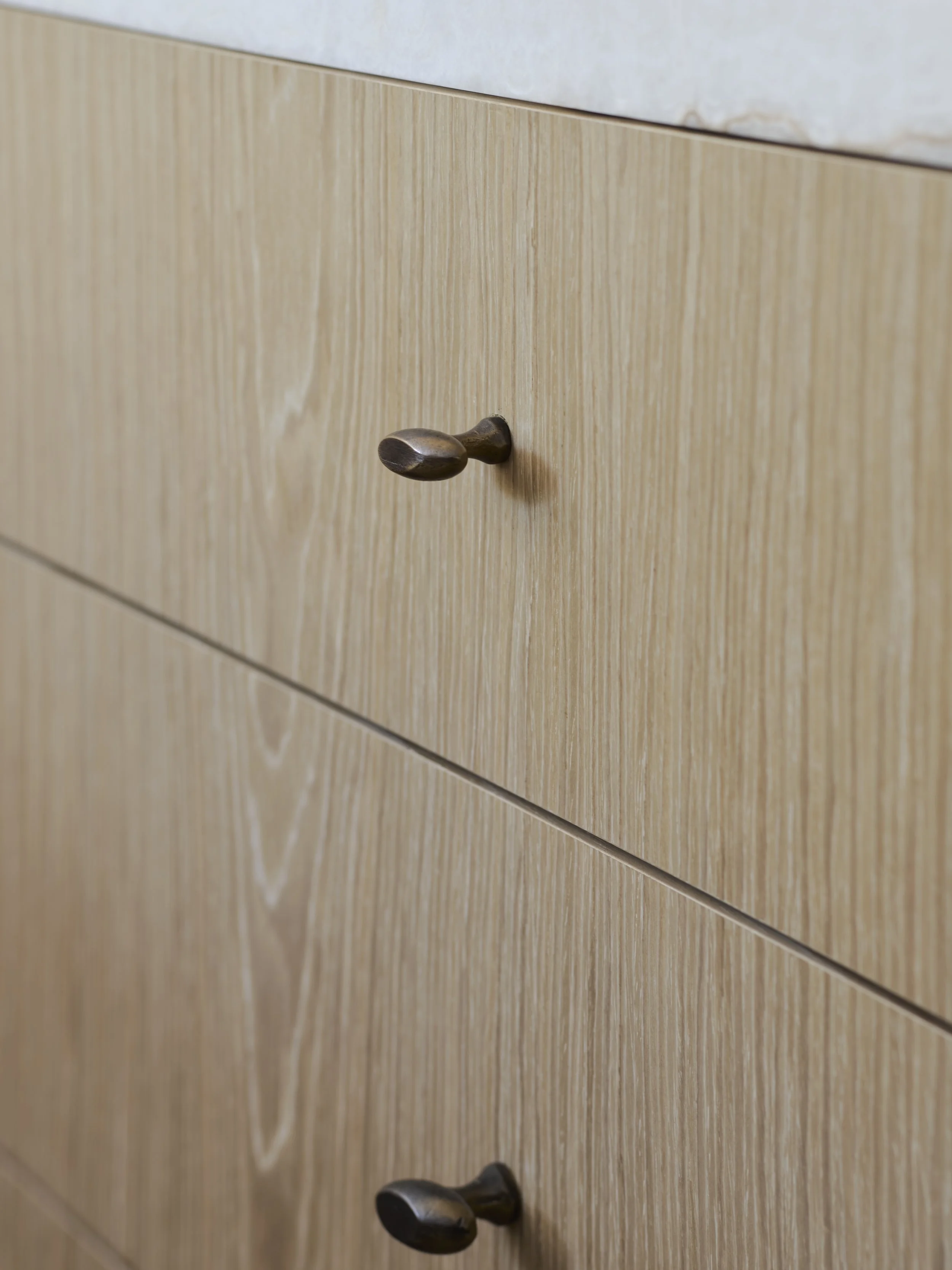 Close-up of a wooden drawer with round, dark-colored knobs.