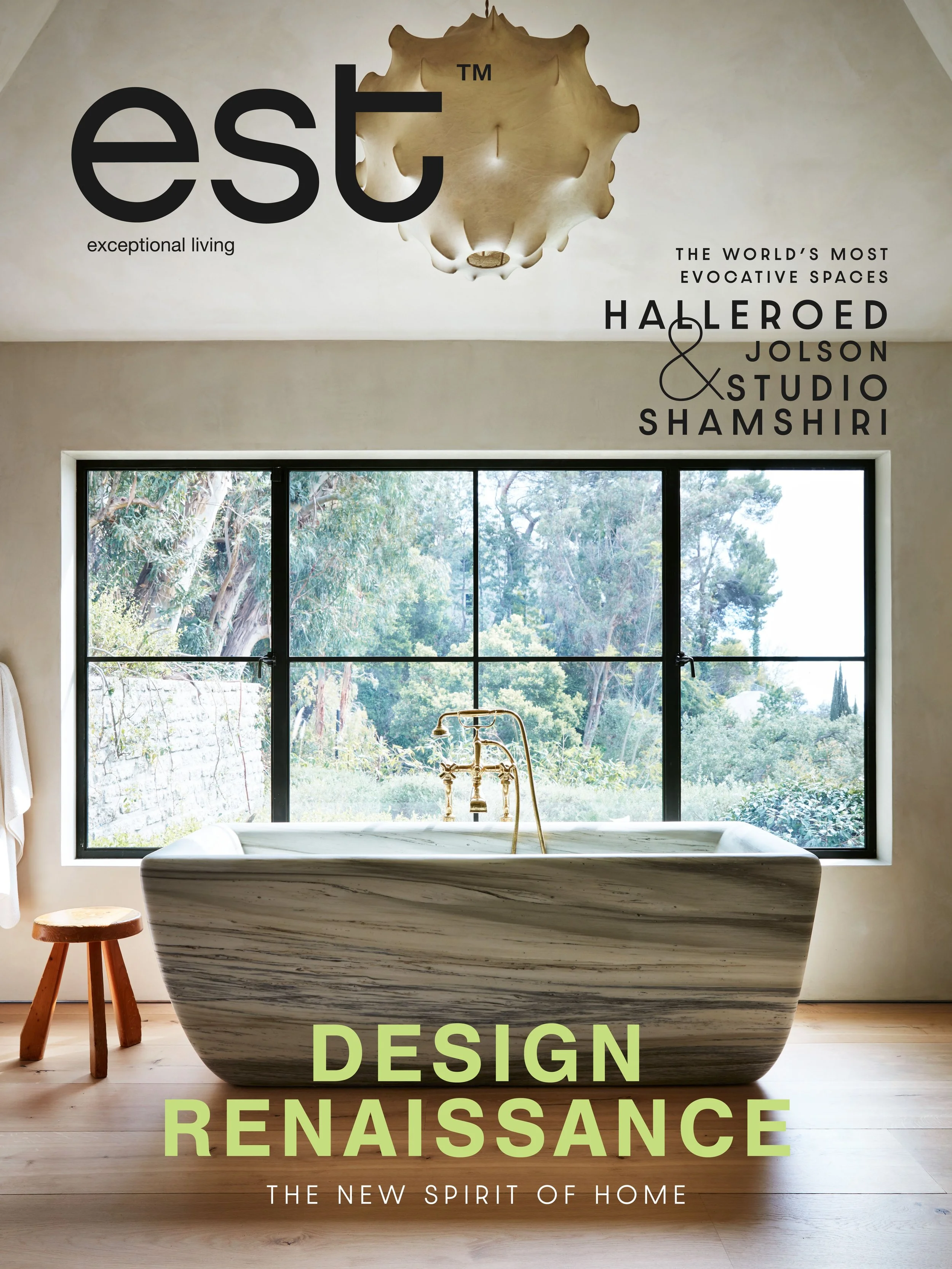 Magazines about interior design, with a top image of a bathroom featuring a bathtub and large window with a view of trees, and text about design renaissance and influential spaces.