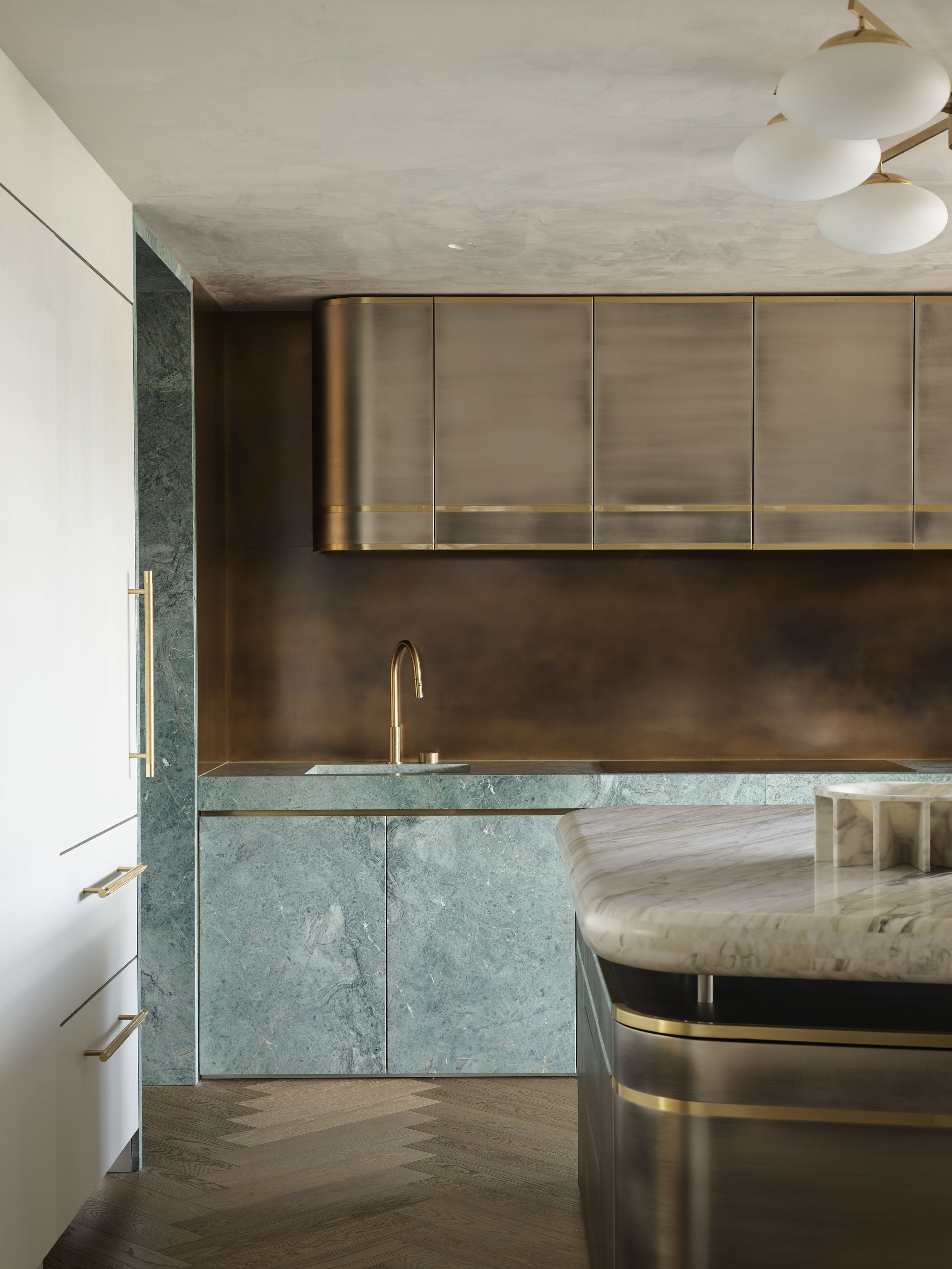 Modern kitchen with green marble cabinets, gold accents, and a marble countertop island.