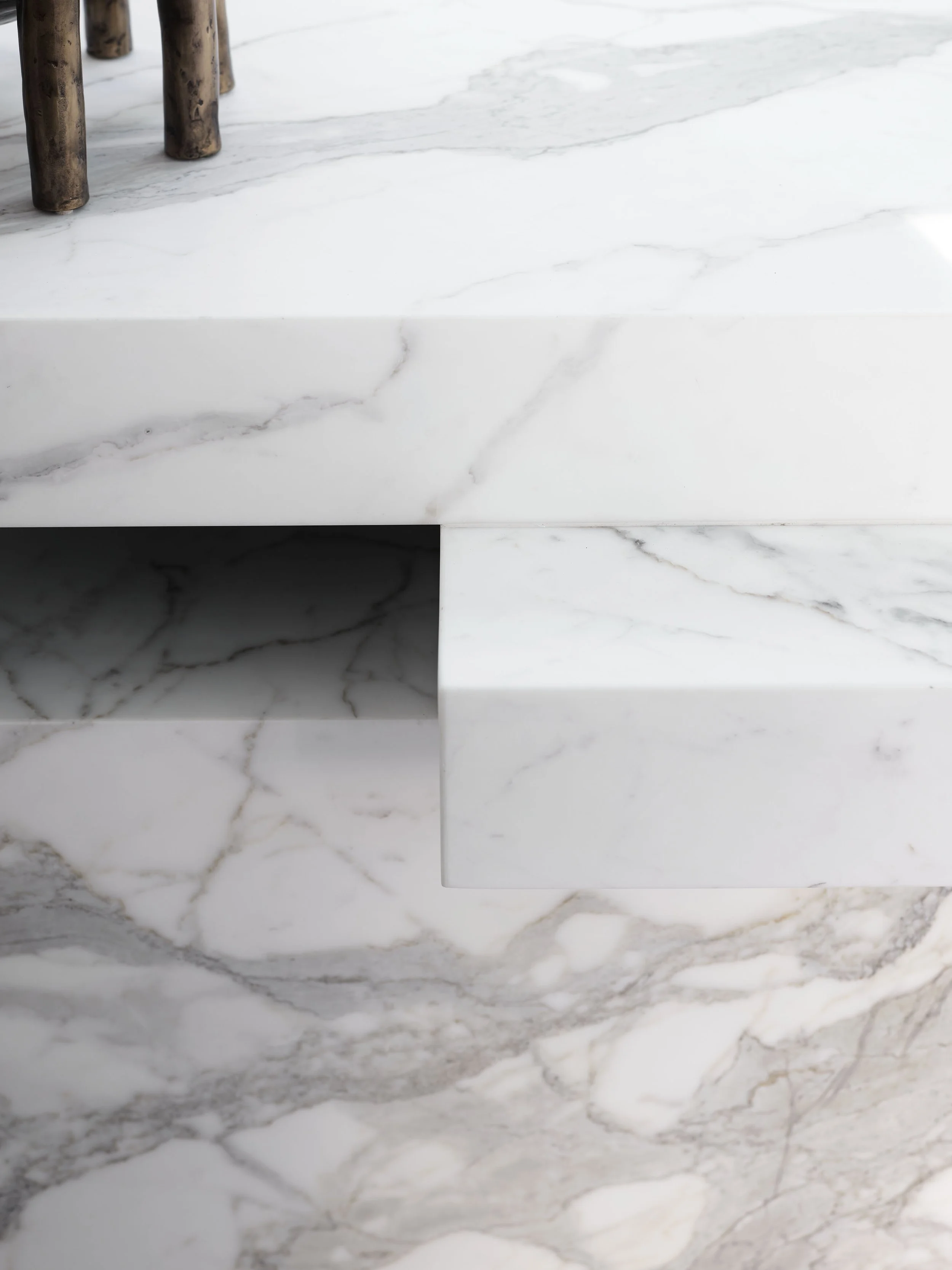 Close-up of a white marble table with a wood sculpture or object on top.