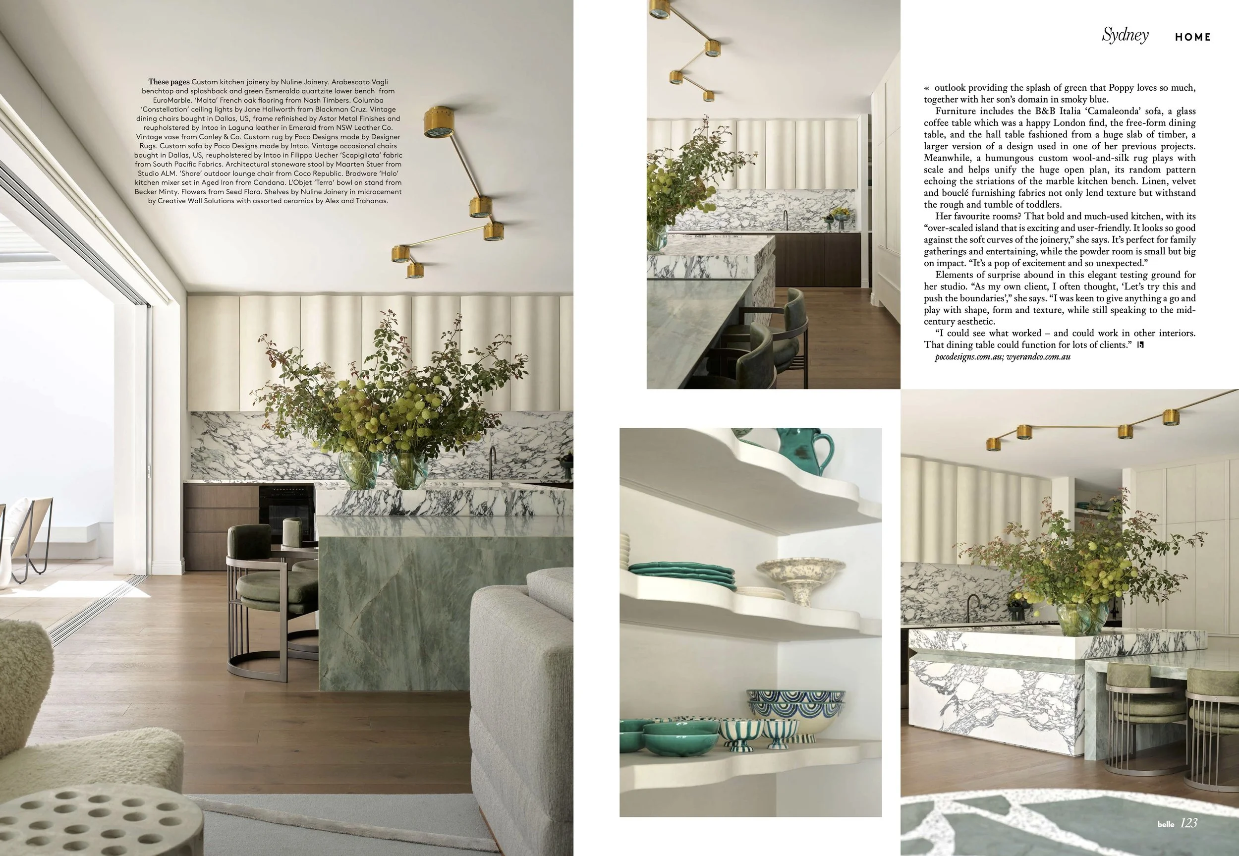 Open-concept kitchen and living space with a marble-topped island, white kitchen cabinets, and a marble backsplash. A large glass vase with greenery is on the island. There is a hanging modern gold ceiling light, and a partial view of a white sofa with textured upholstery. A separate inset shows shelves with turquoise dishware and decorative bowls. Overall, the space has a minimalist and modern aesthetic with natural light and warm wood flooring.