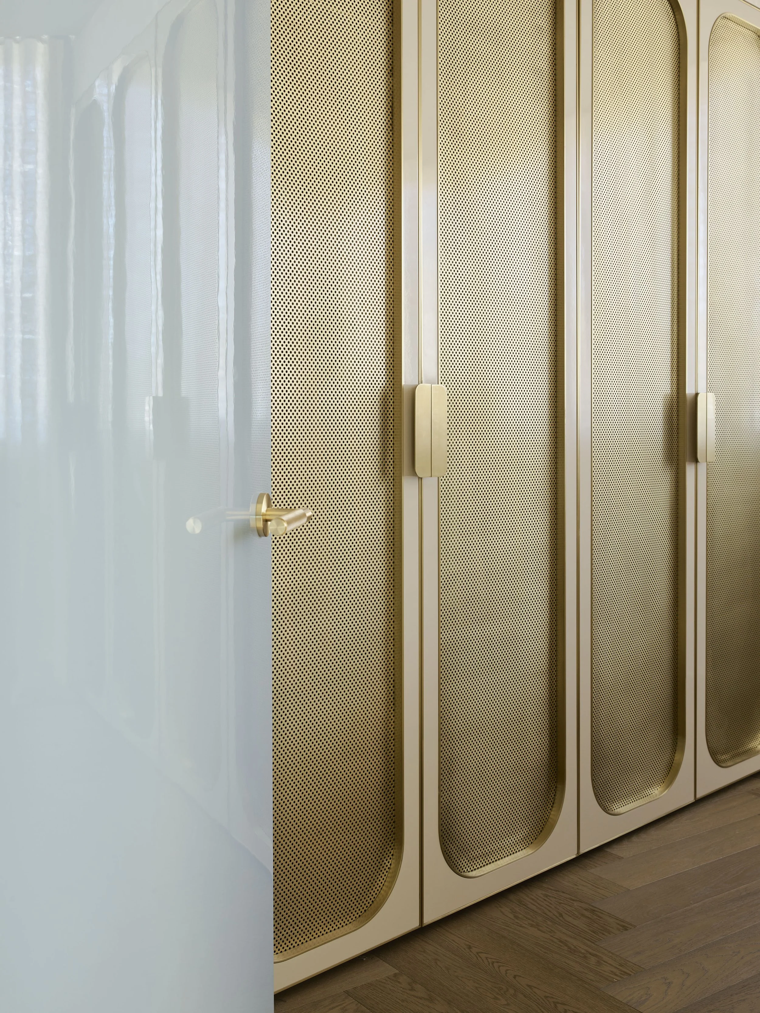 Gold-colored lockers with rounded tops and perforated doors, partially open door on the left with visible handle, wooden floor.