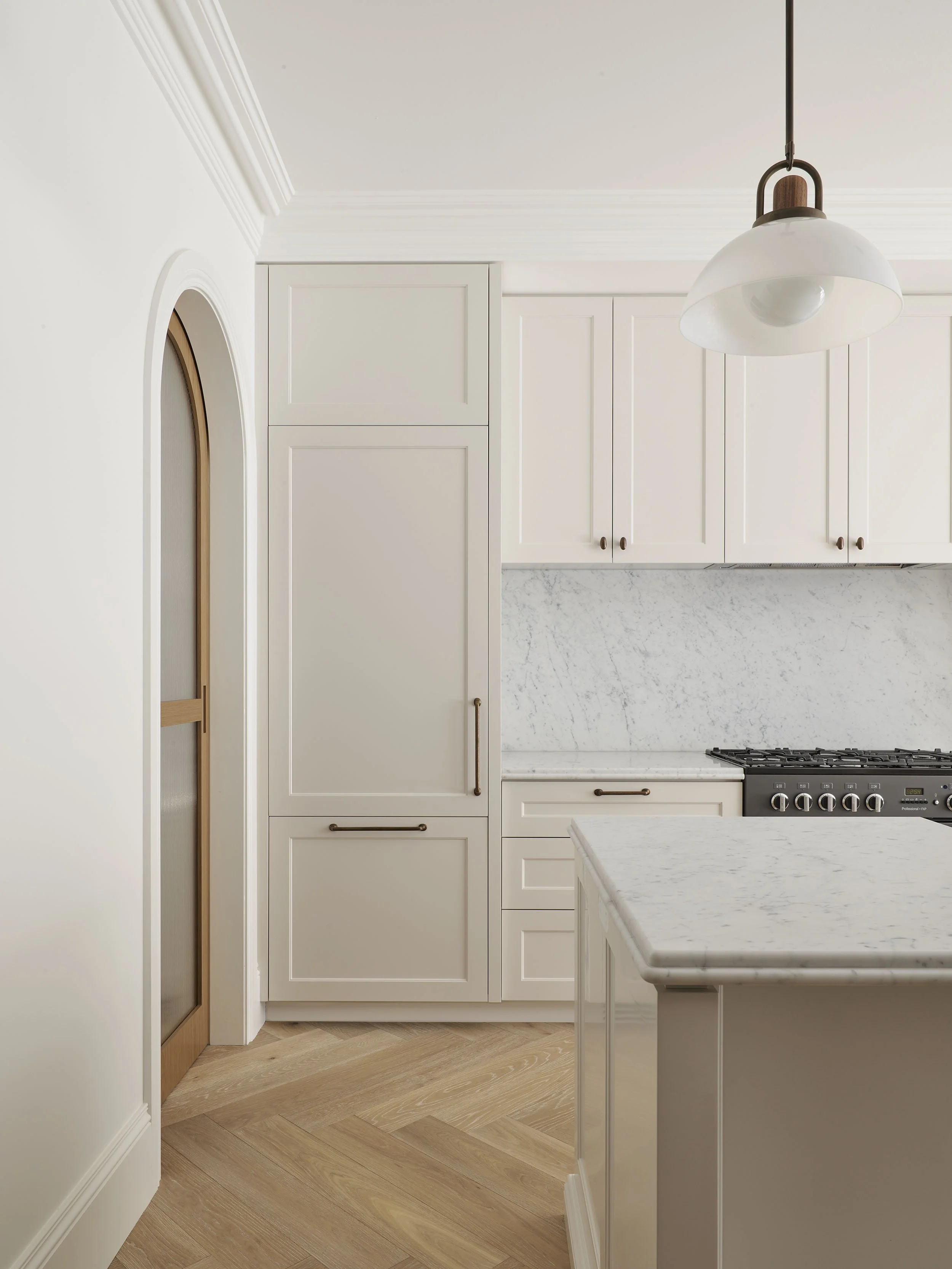Kitchen with white cabinets, marble backsplash, and wooden flooring, featuring a hanging light fixture.