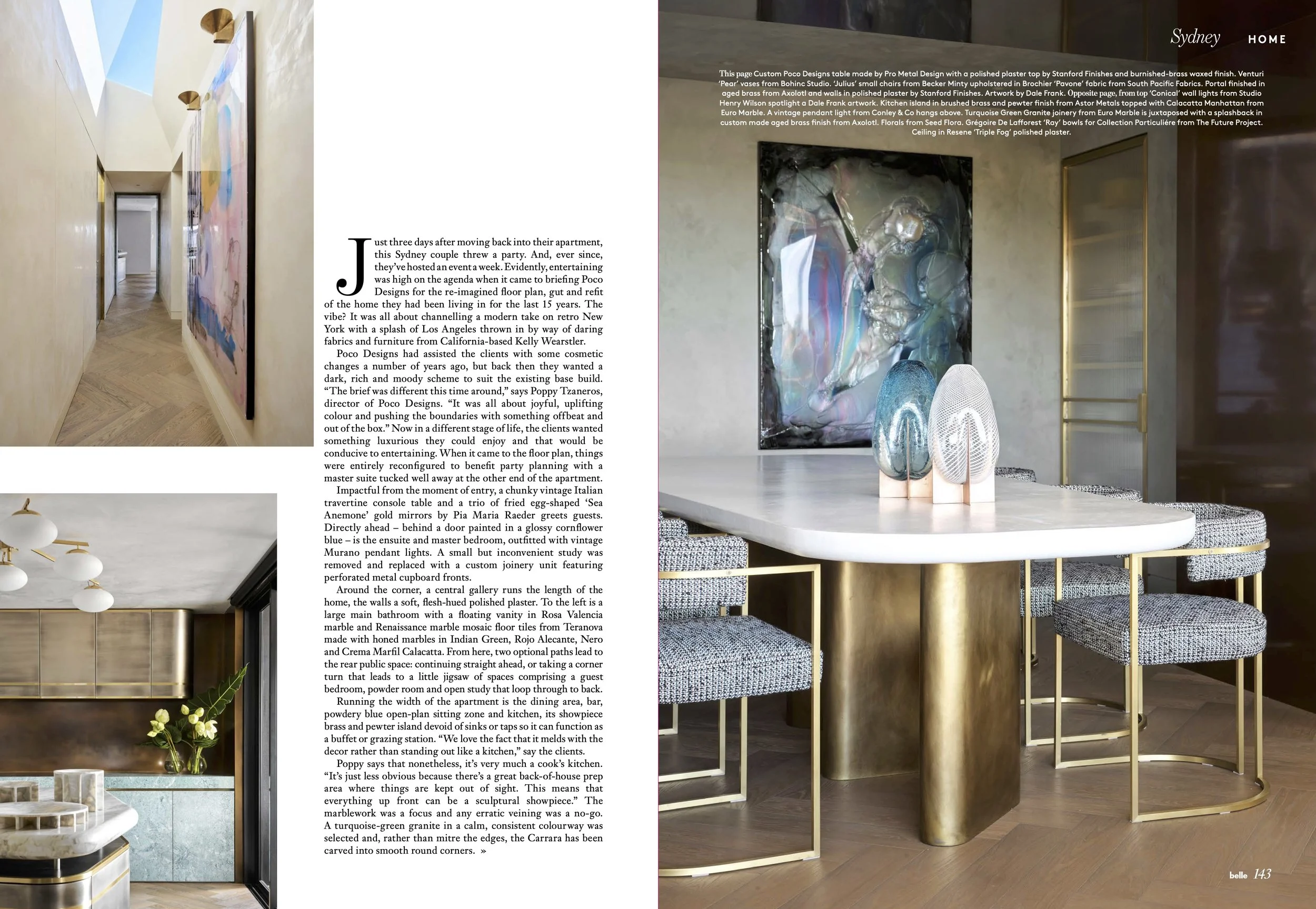 Photograph of a modern, luxurious interior showing a round marble dining table with a gold base, surrounded by grey upholstered chairs with gold frames. On the table, there are decorative glass objects, including abstract sculptures. In the background, a textured wall with an abstract colorful painting and a gold-framed glass door are visible, along with part of a black and gold sideboard and a bouquet of flowers.