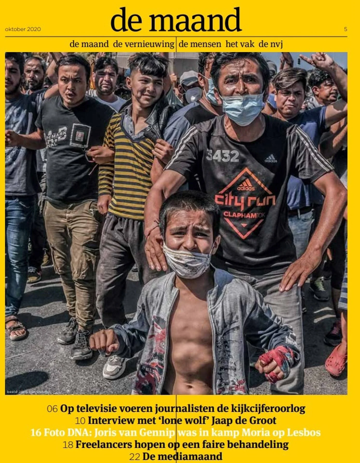 A group of people protesting, with the focus on a man wearing a face mask and a young boy in front of him, also wearing a mask, in a public demonstration during daytime.