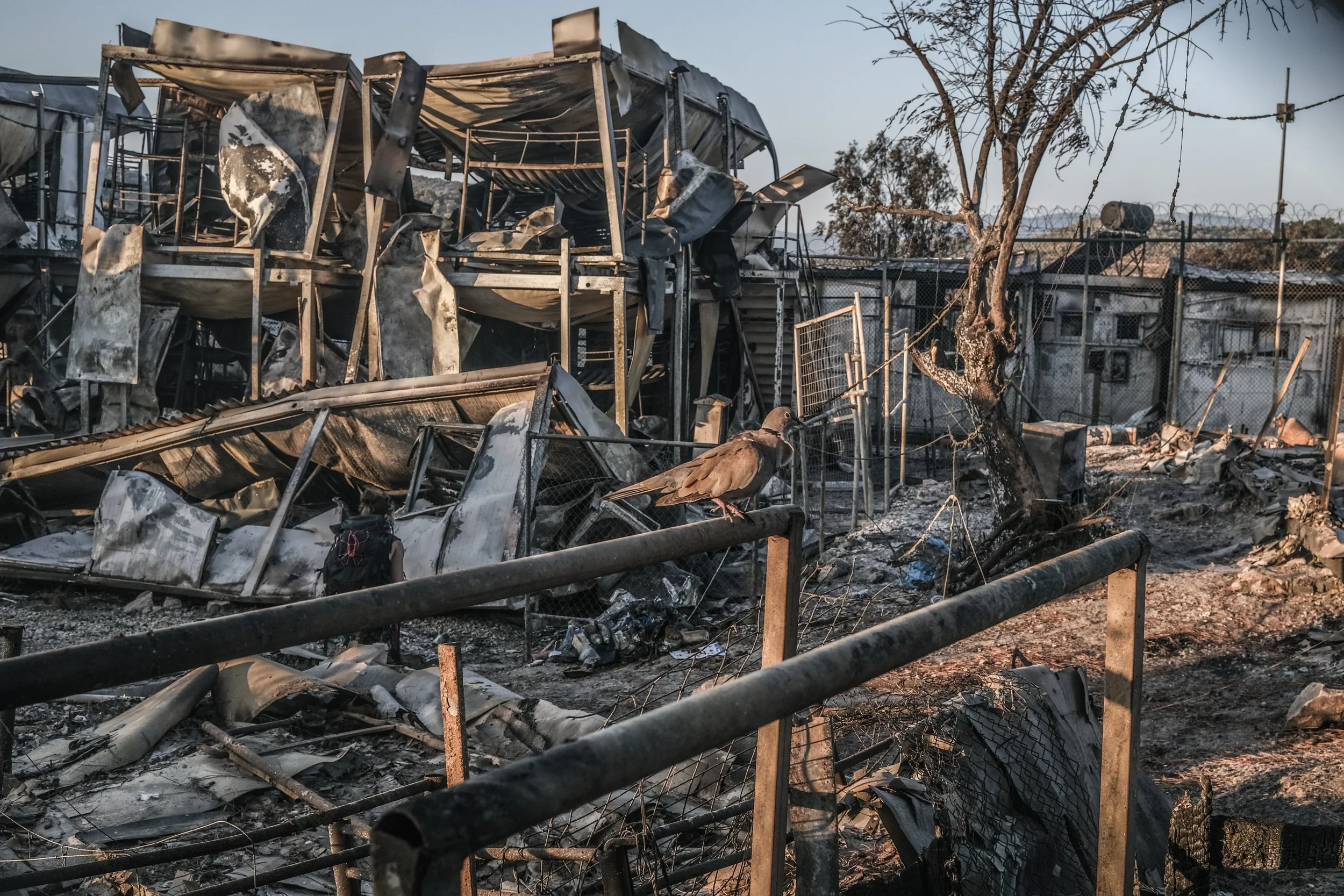 Ruined and charred remains of a building, with twisted metal and scorched debris, showing a scene of destruction after a fire.