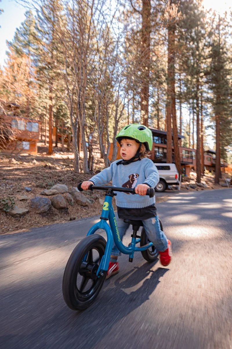  Toddler riding blue balance bike down neighborhood road, Lake Tahoe, documentary family photography 