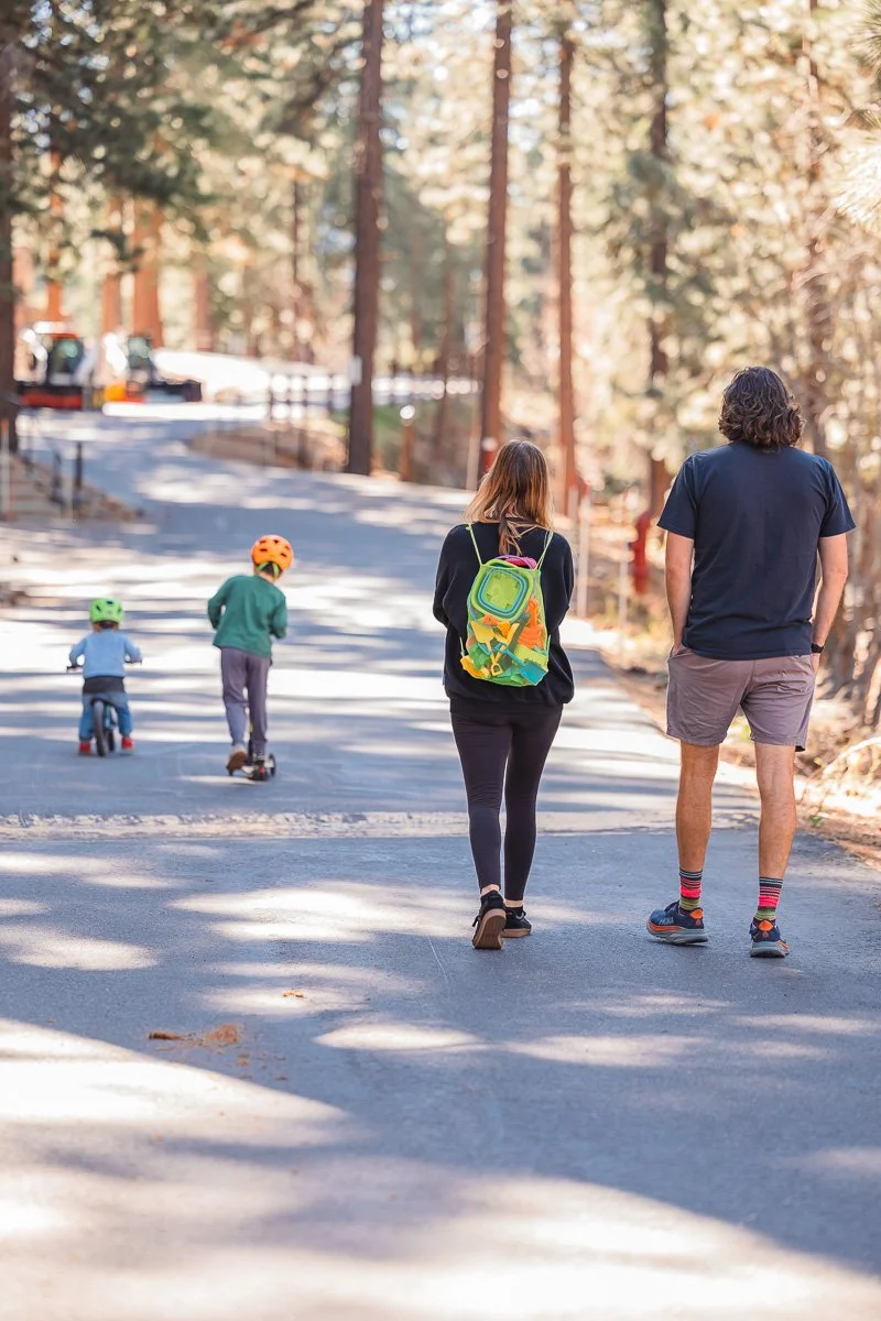  Family walking tree-lined road with two boys on balance bike and scooter, Lake Tahoe neighborhood, documentary family photography 