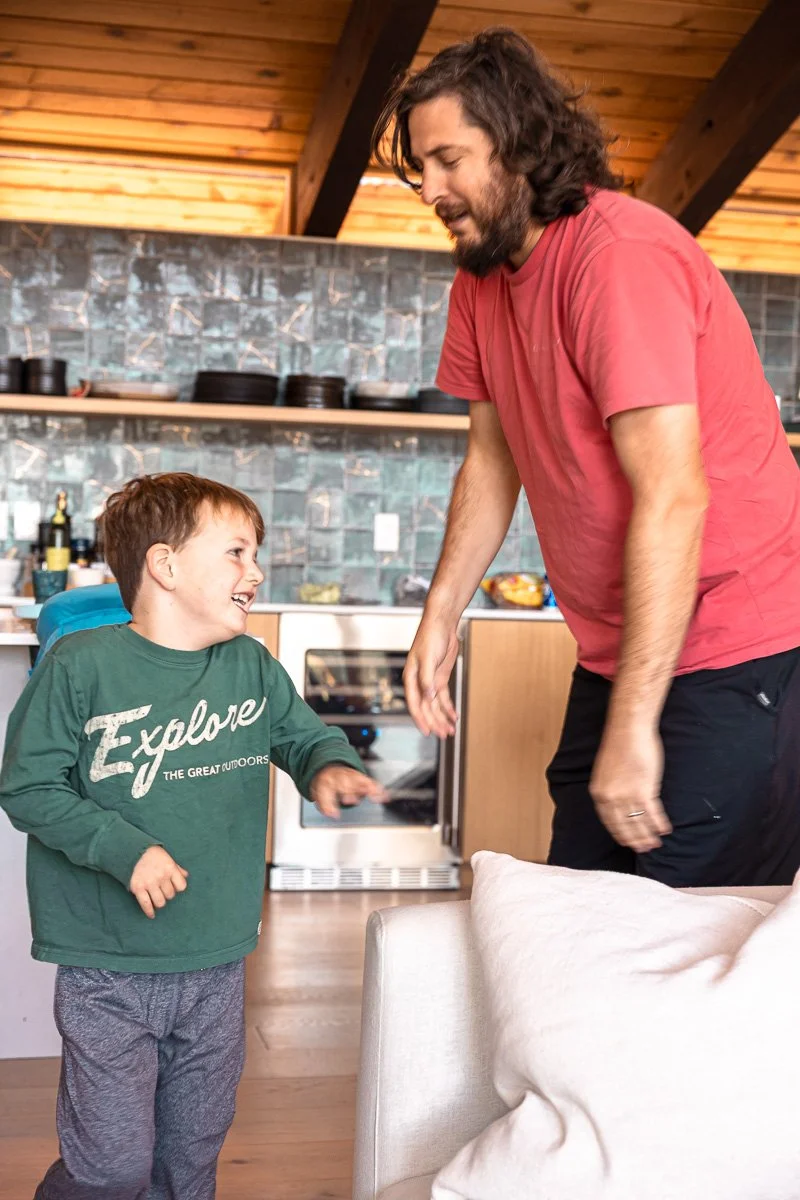  Dad and son dancing together in cabin kitchen, Lake Tahoe, documentary family photography 