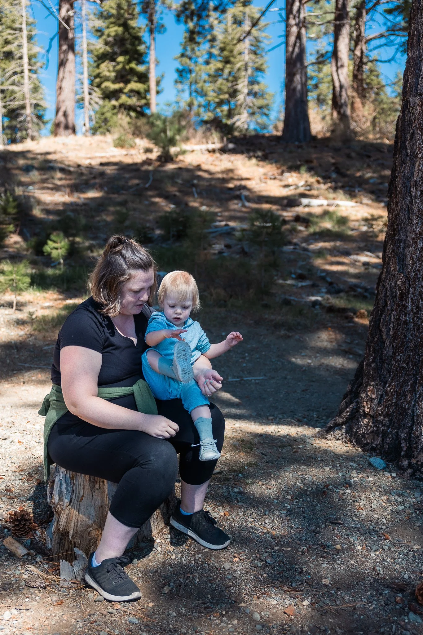 Mom Putting Shoes Back on Toddler on Forest Trail