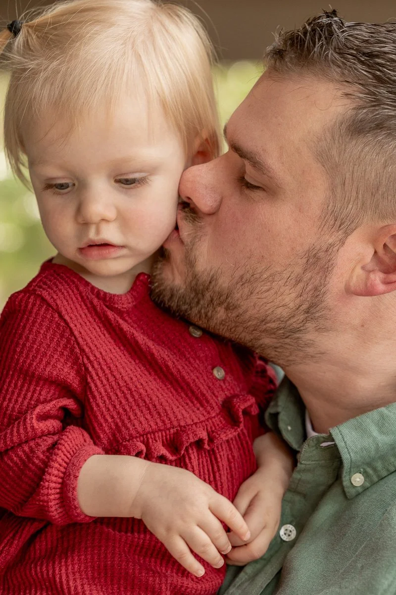 Father kissing his toddler daughter on the cheek during a documentary family photography session at Camp Richardson, Lake Tahoe