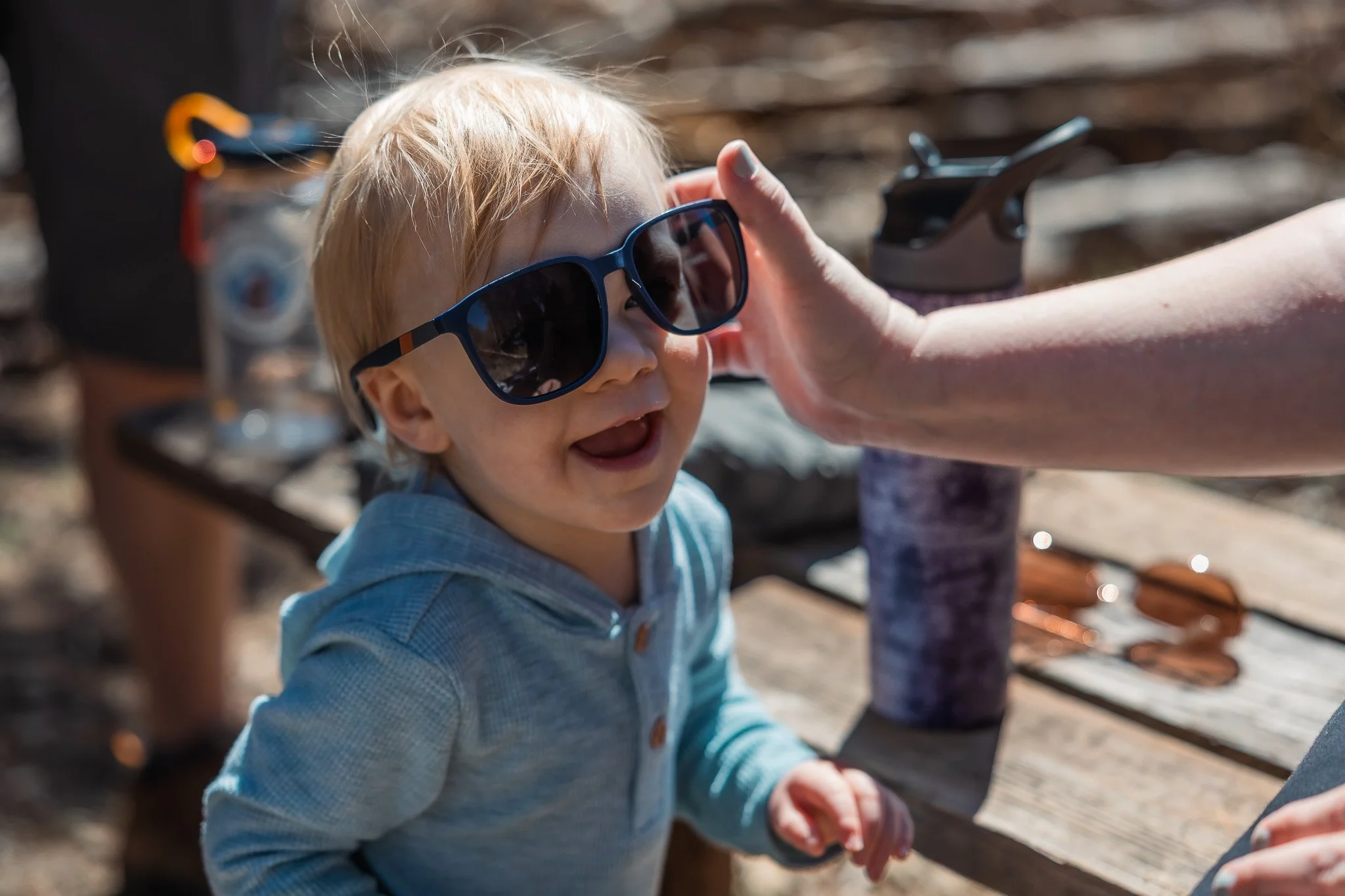 Toddler wearing oversized sunglasses at Fallen Leaf Lake, hand adjusting them, documentary family photography