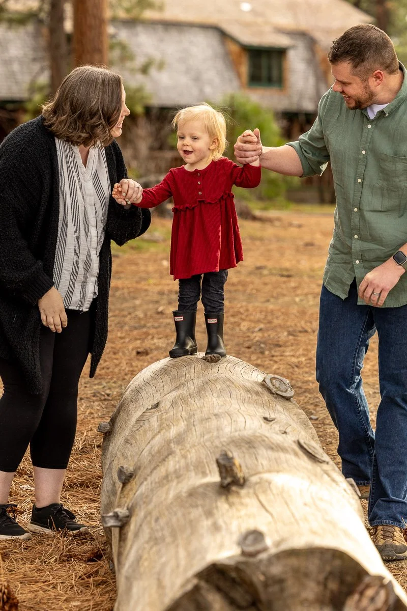 Parents holding their toddler's hands between them on the grounds at Camp Richardson during a documentary family photography session at Lake Tahoe