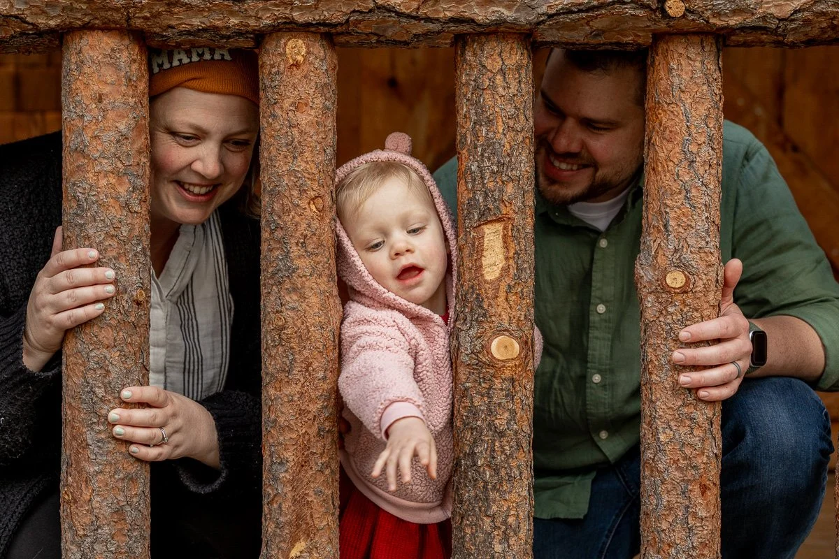 Family playing peekaboo through the log railings of a cabin at Camp Richardson during a documentary family photography session at Lake Tahoe