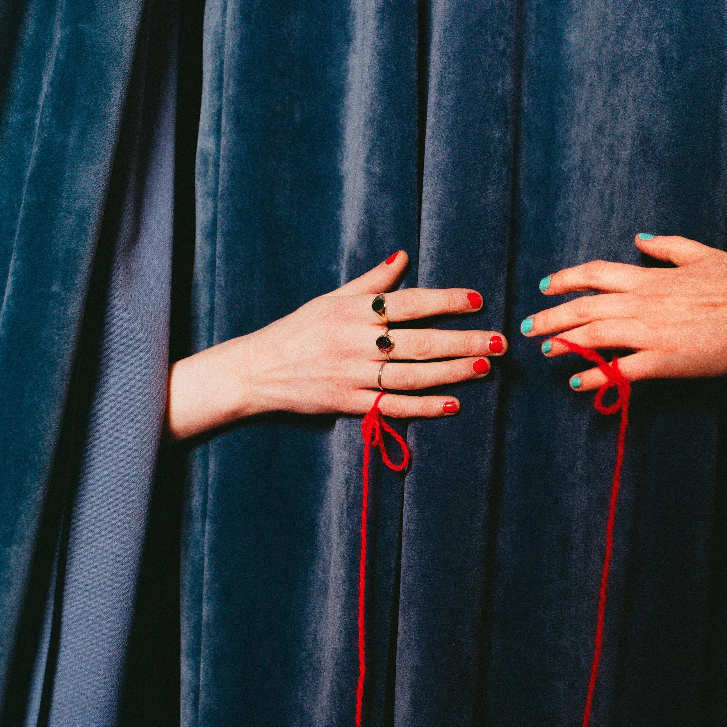 Carla J Easton Album artwork - I Think That I Might Love You Two hands with colorful nail polish and rings hold a velvet curtain with red string ties.