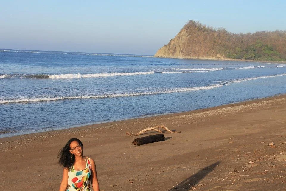 Majda, founder of Namajo, smiling on a beach during one of her 50+ country travels