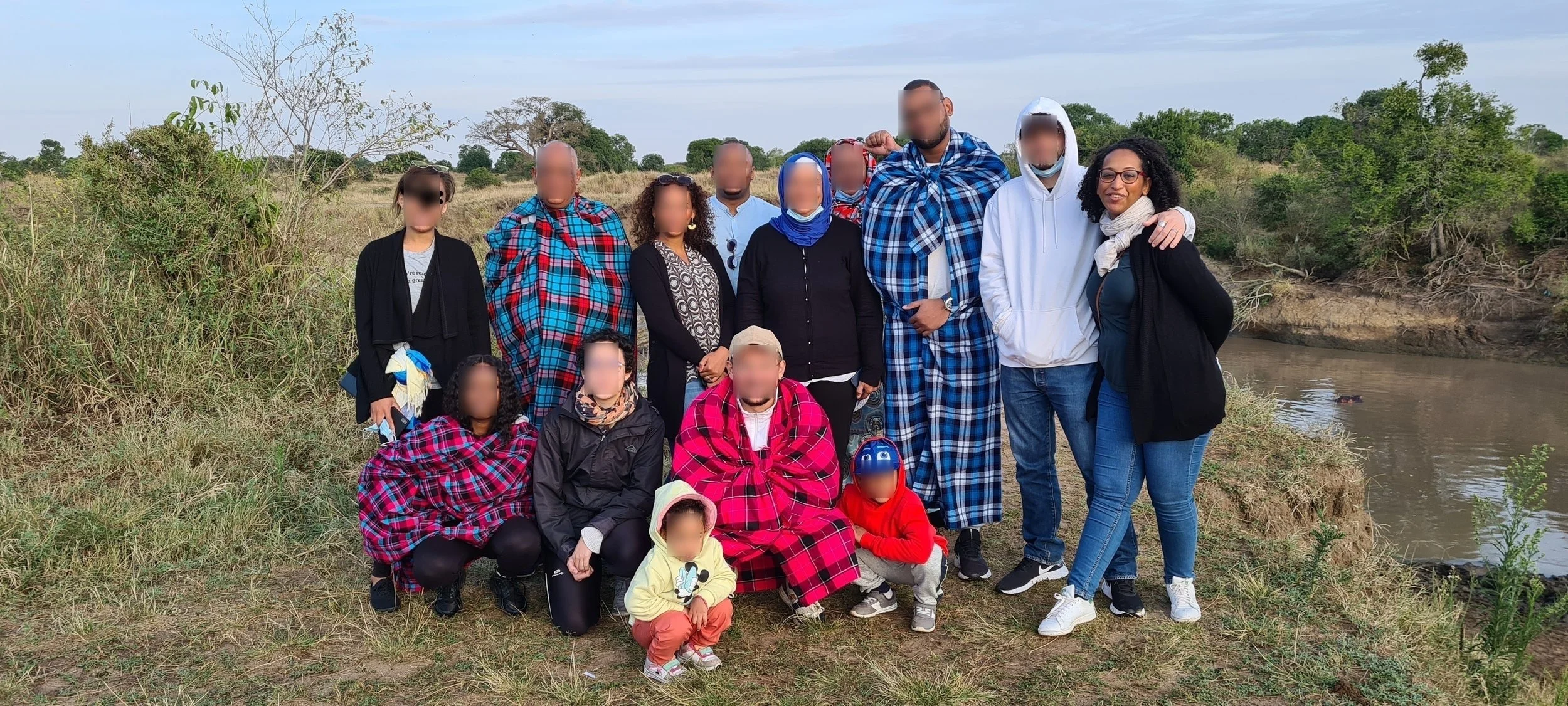 Majda with a group of travelers wearing traditional Maasai blankets in East Africa - intergenerational group travel planned by Namajo