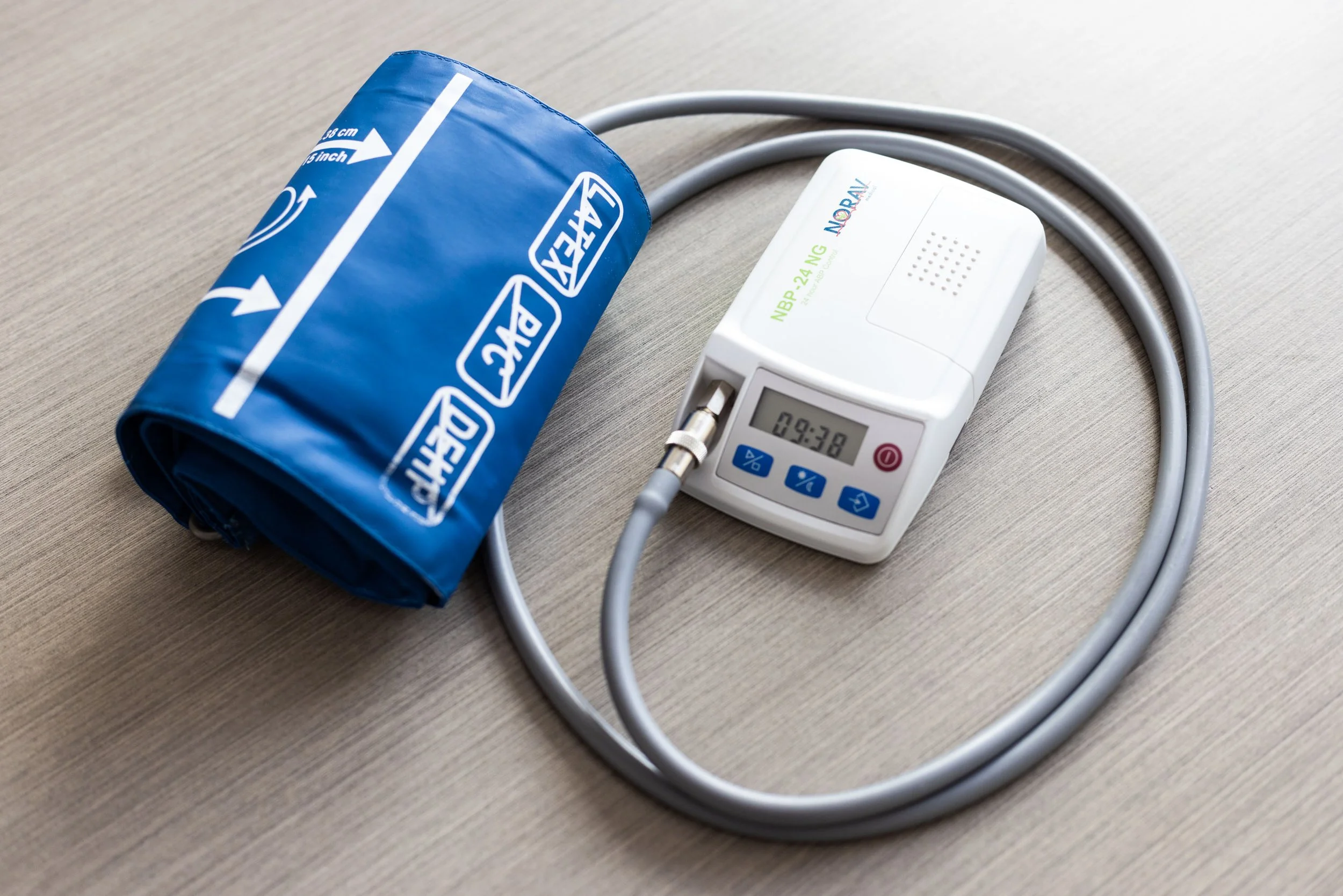 Blood pressure monitor with cuff on a wooden surface.