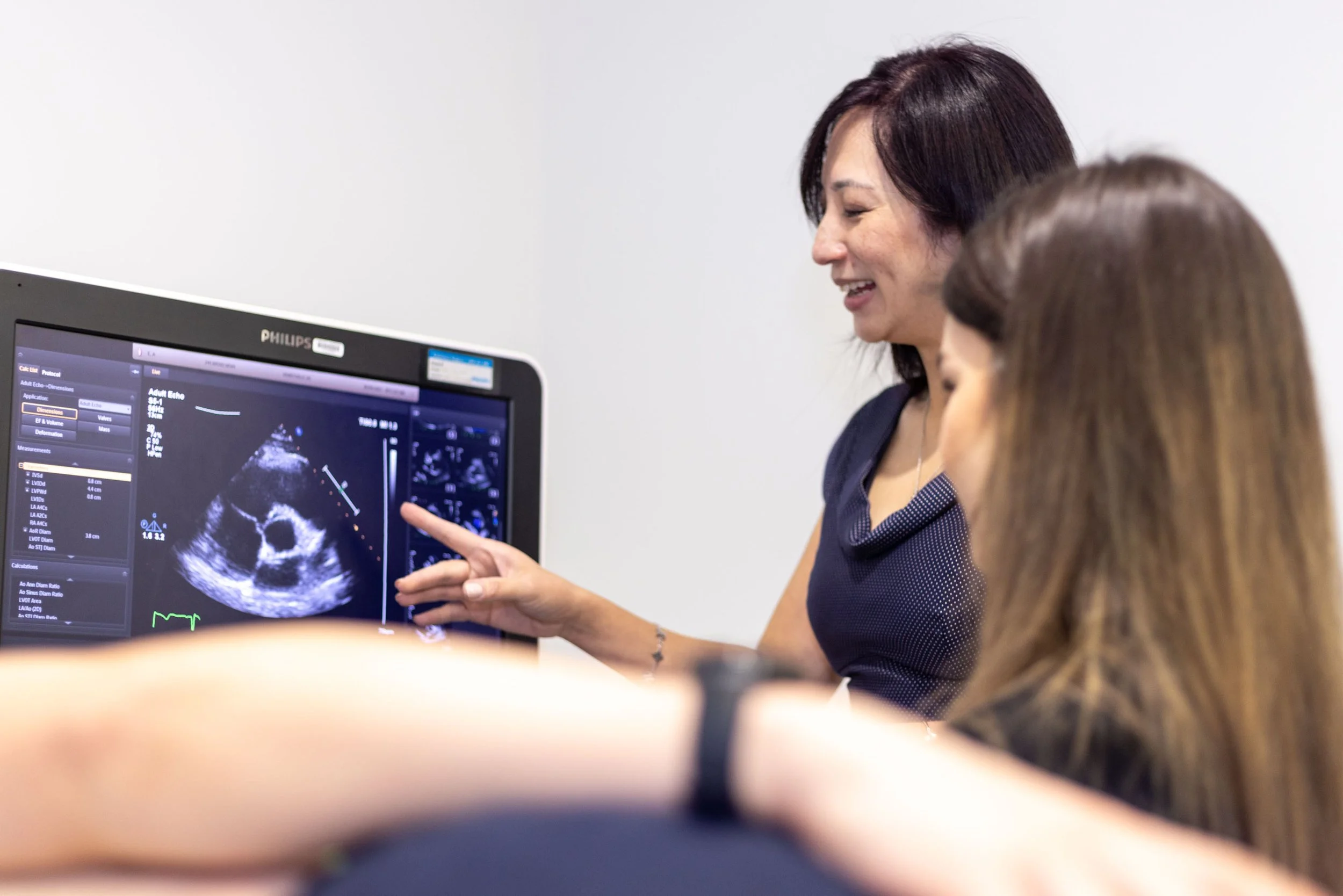 A medical professional showing an ultrasound image to a group of people in a clinical setting.