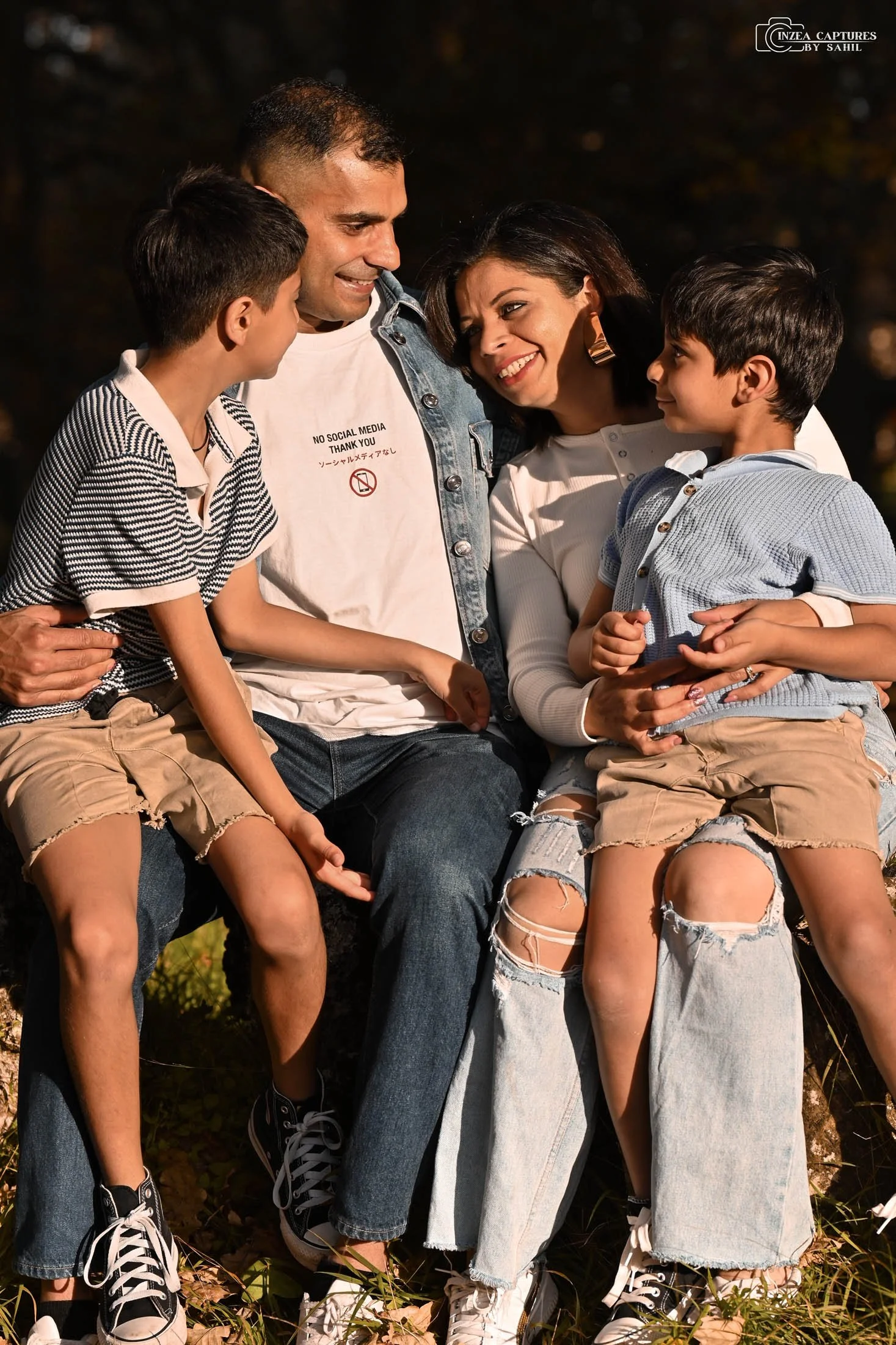 A family of four sitting outdoors at night, smiling and enjoying each other's company.