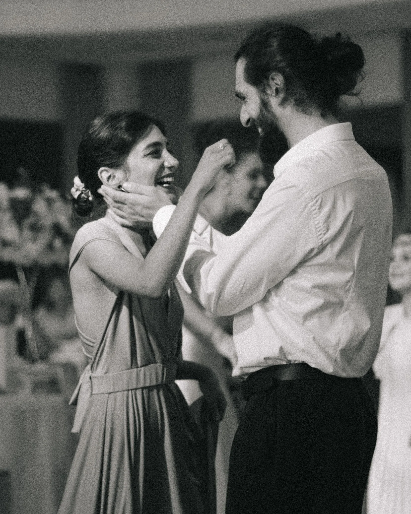 A black and white photo of a man and woman dancing closely, smiling, with the woman touching the man's face.