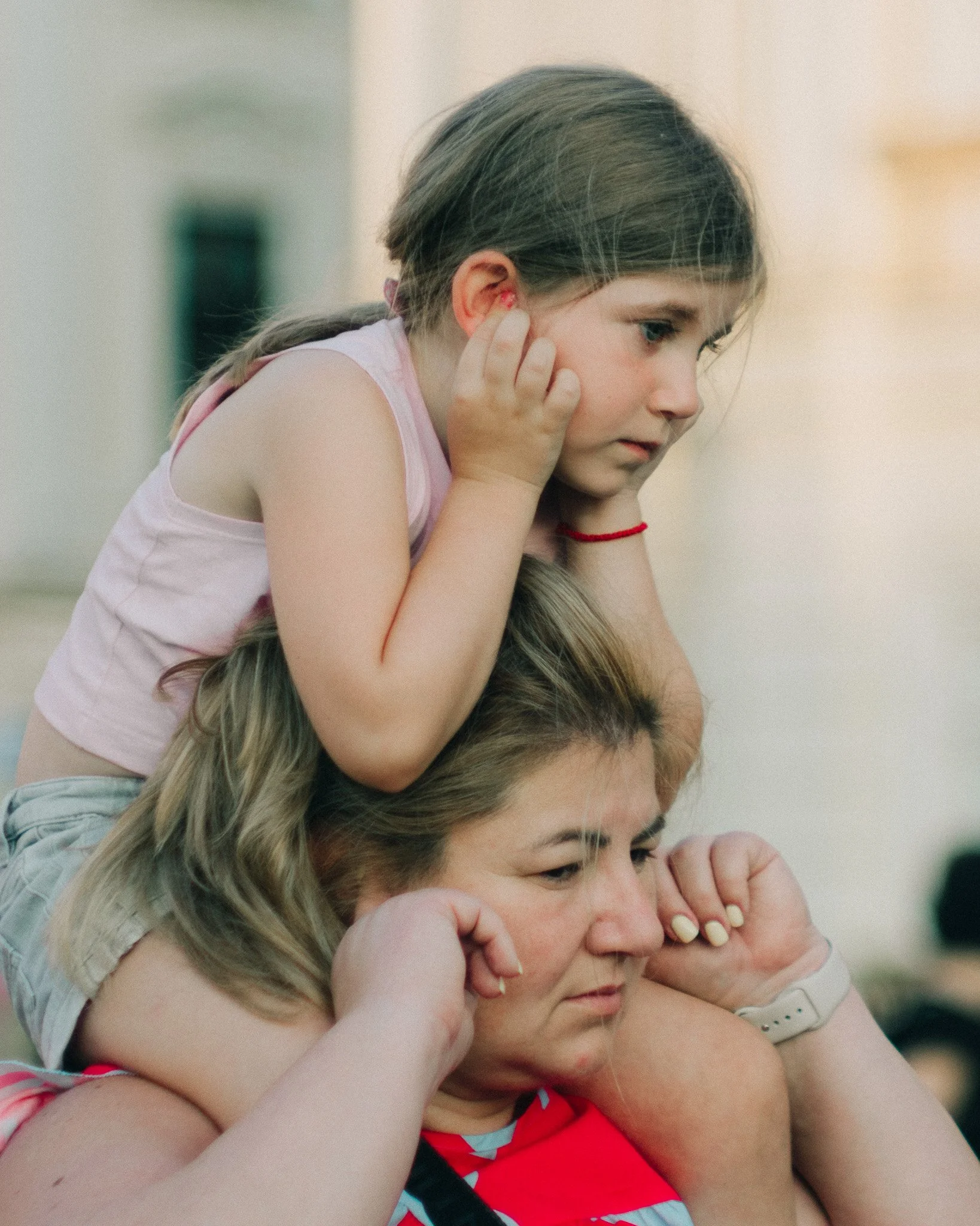 A young girl and a woman are listening to something with their hands over their ears caused by sound.