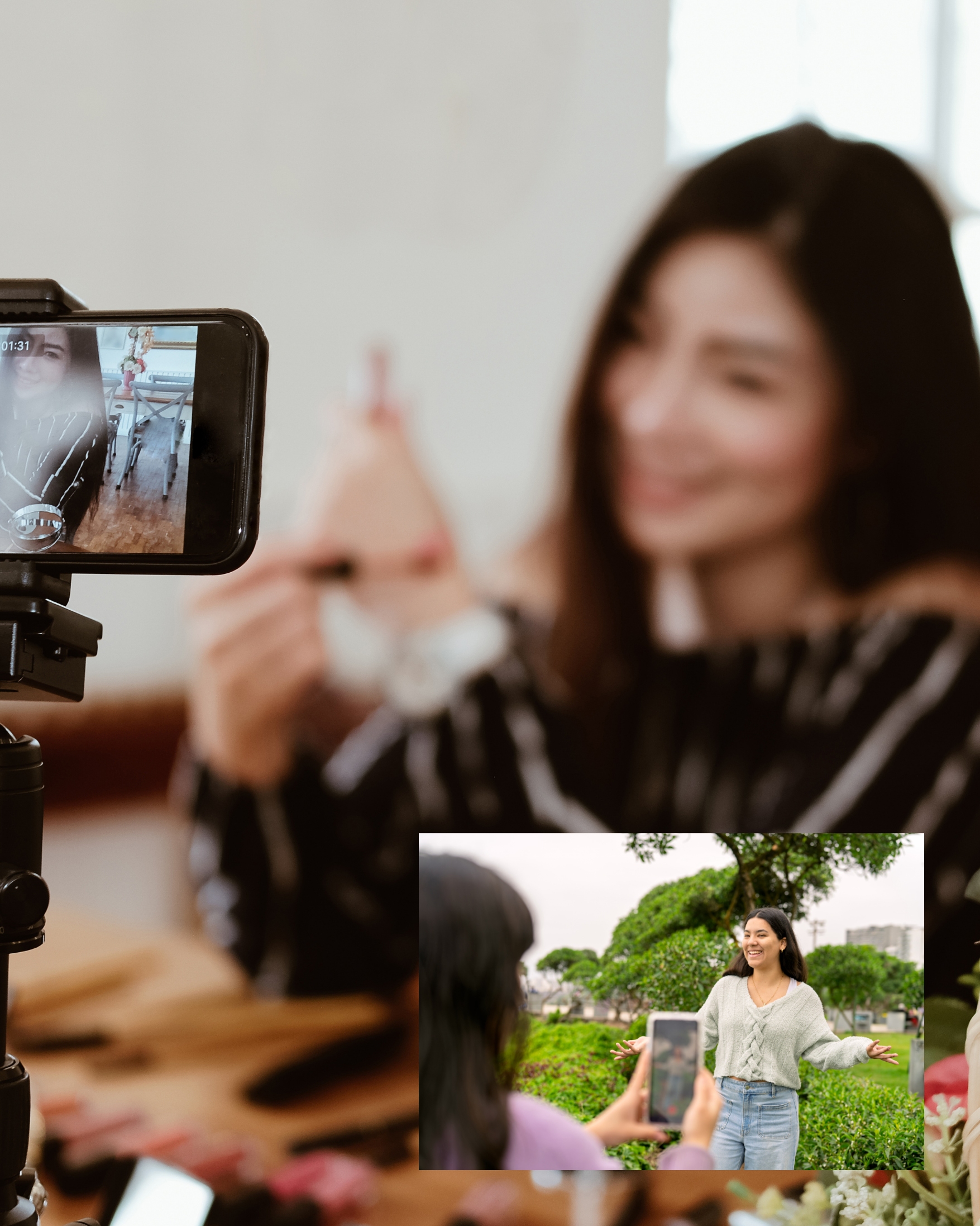 A woman taking a selfie of another woman outdoors in a park with trees and greenery.