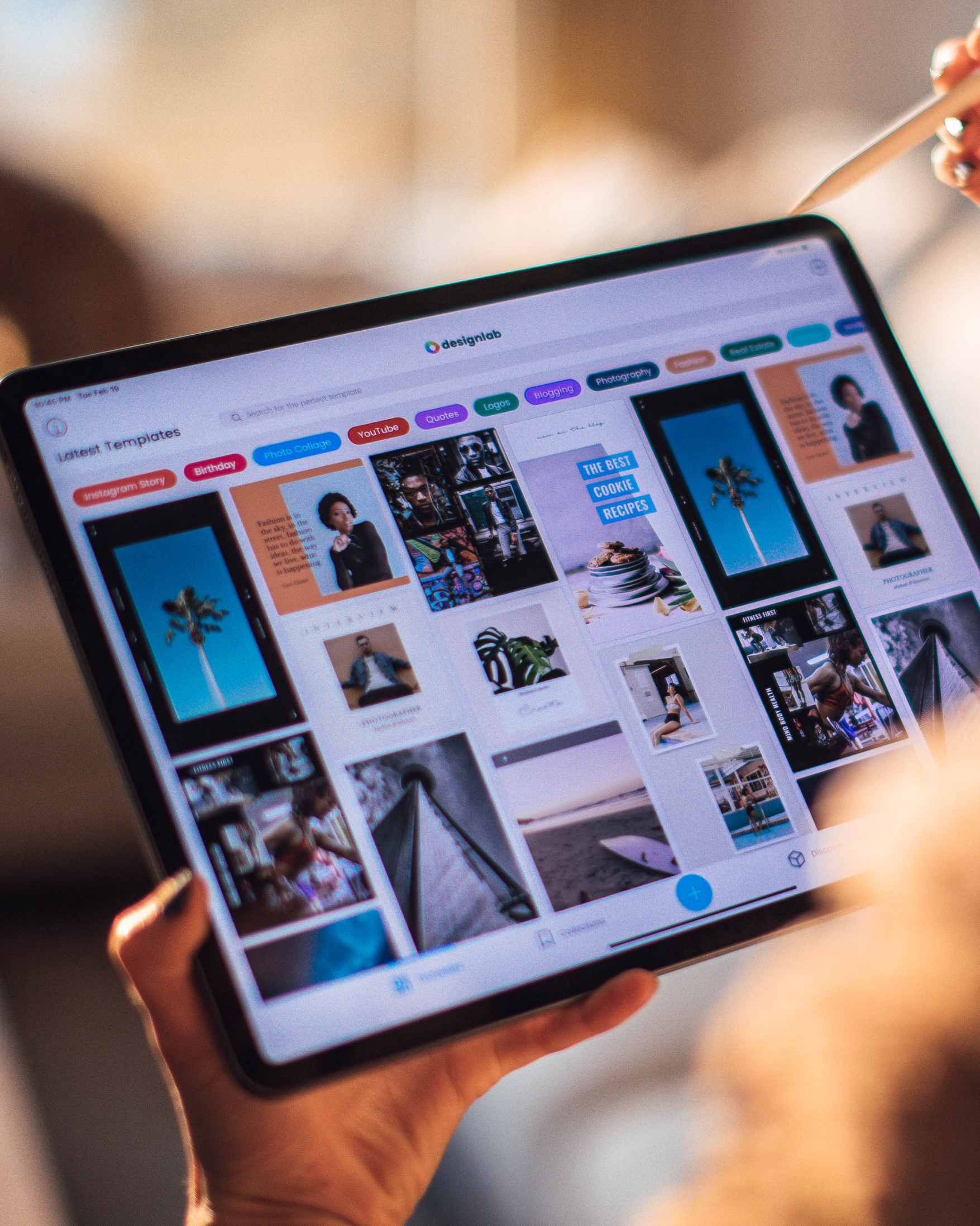 Person holding a tablet displaying a Pinterest board with various photos and colorful category tags