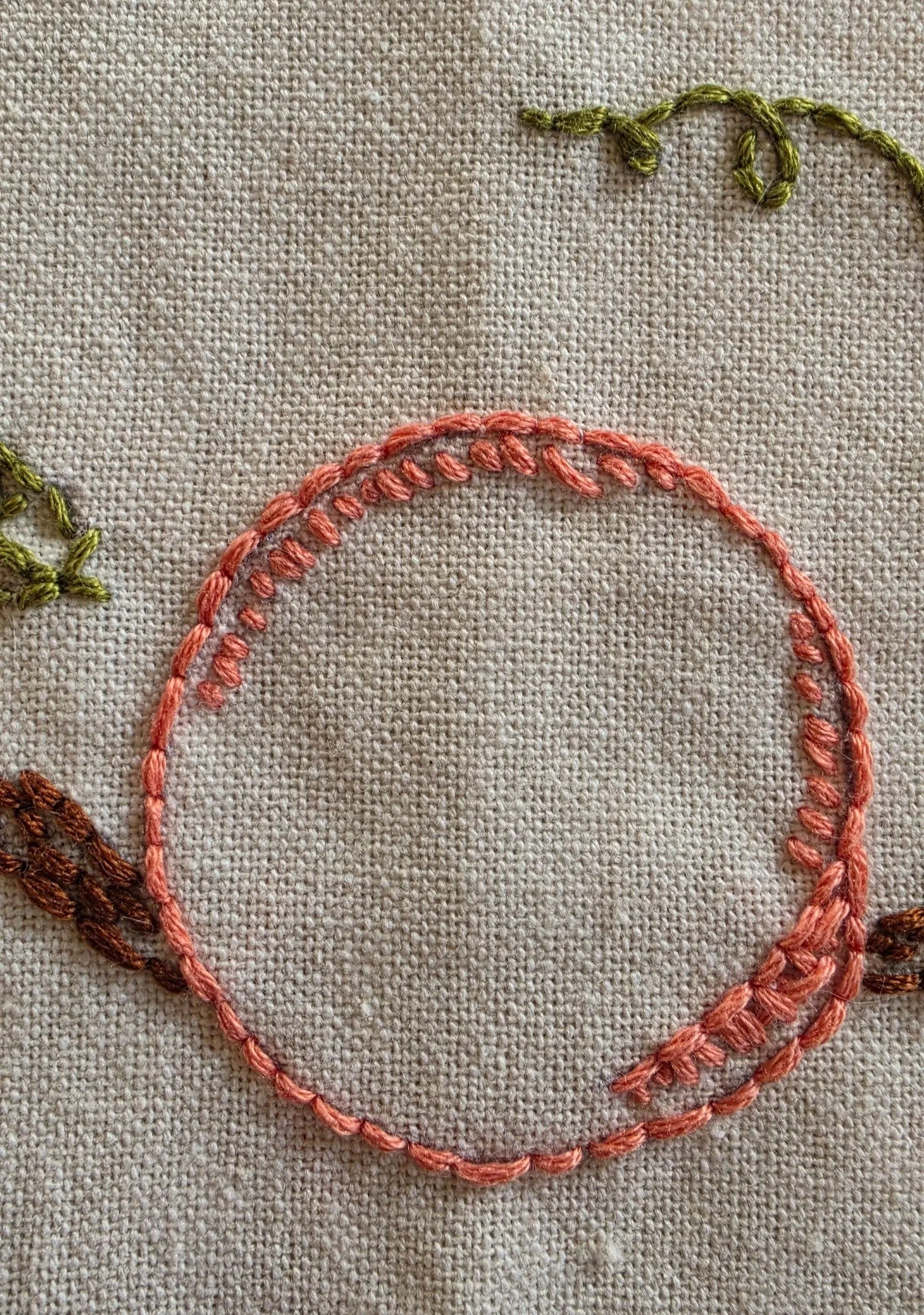 Close-up of the word PEACHES stitched in coral thread beneath the embroidered peach design.